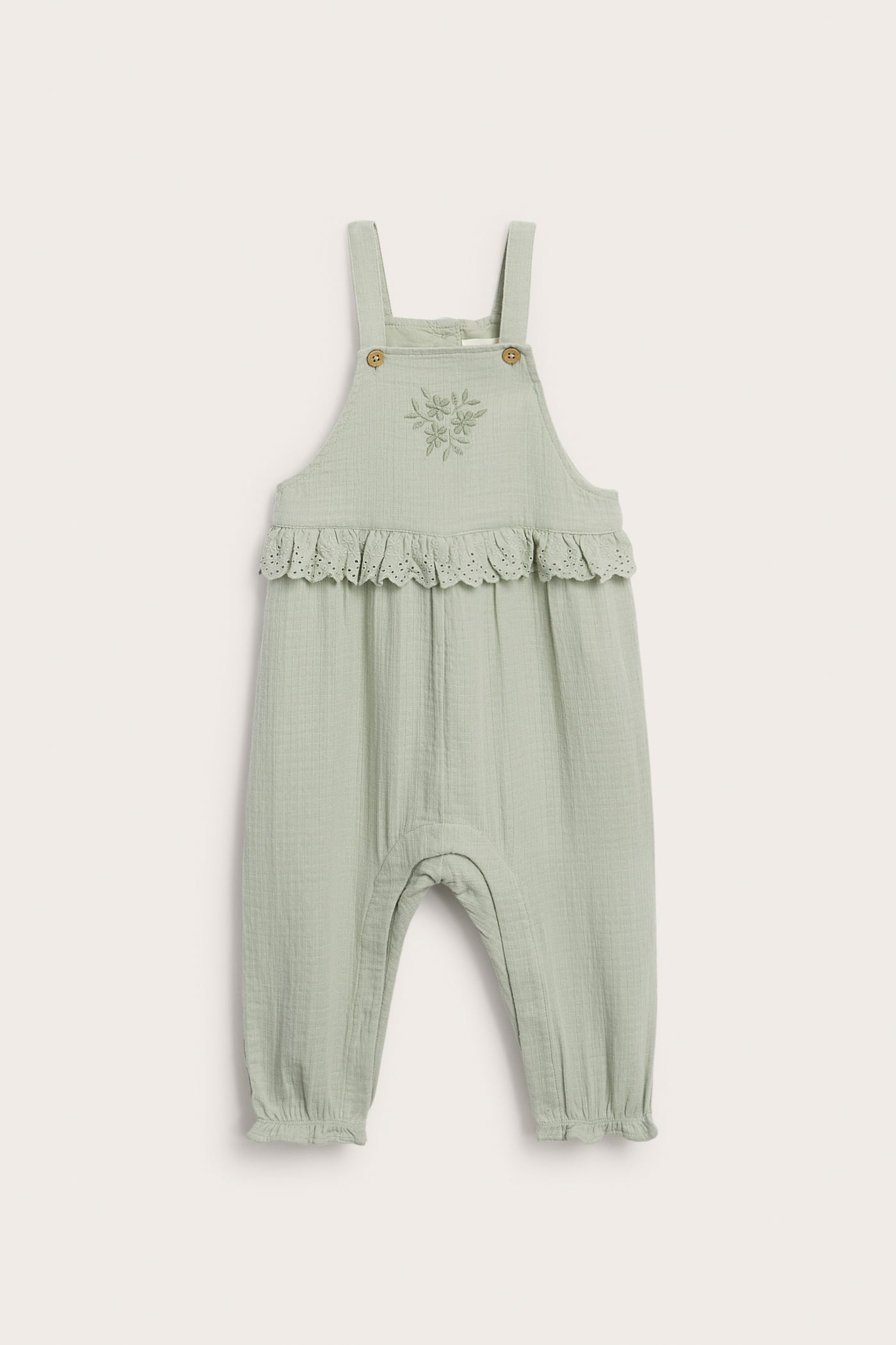 Front view of light green baby cotton overalls with flower embroidery and lace ruffle at the waist.