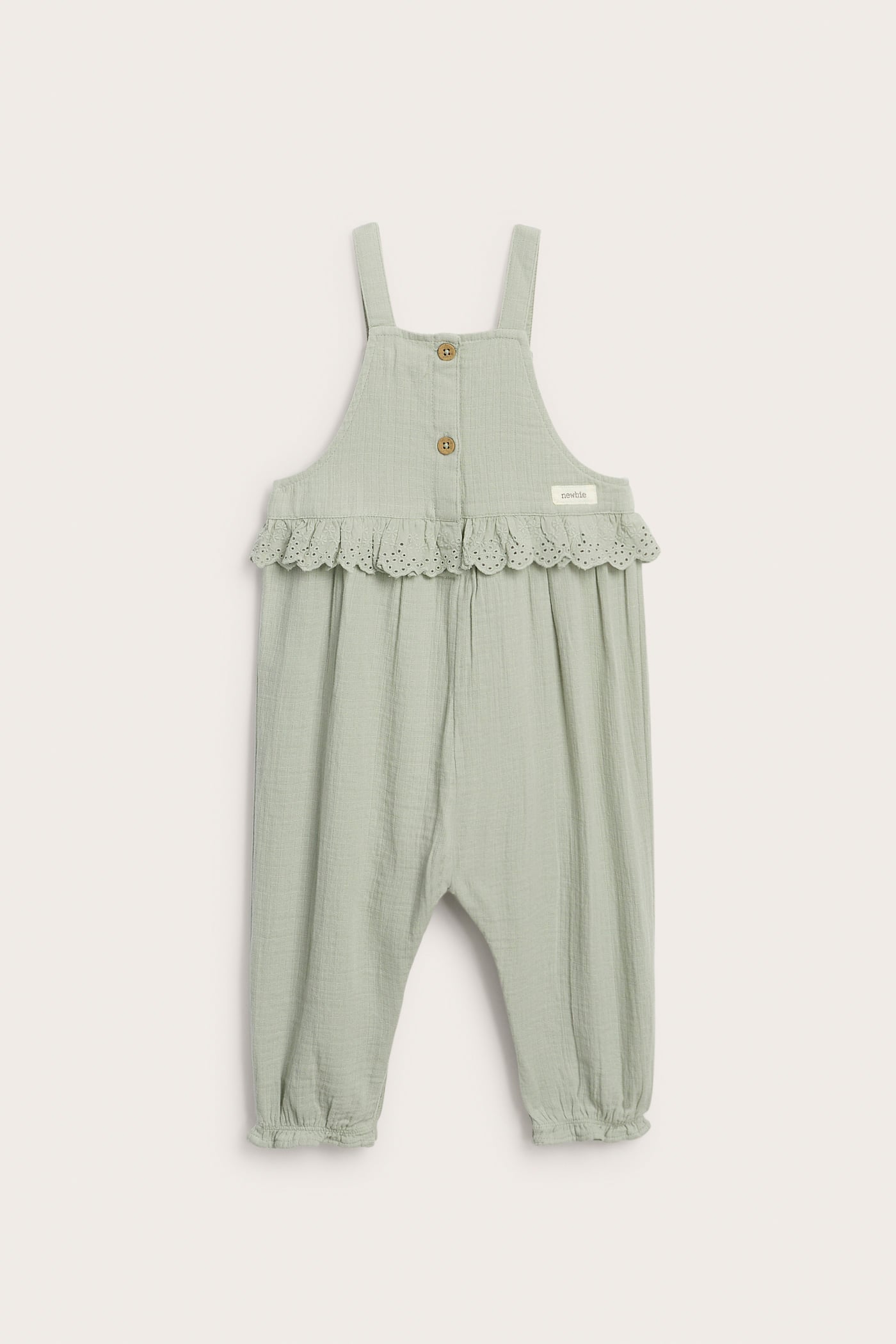 Front view of baby's sage green cotton overalls with eyelet lace ruffle, chest embroidery, and adjustable straps.