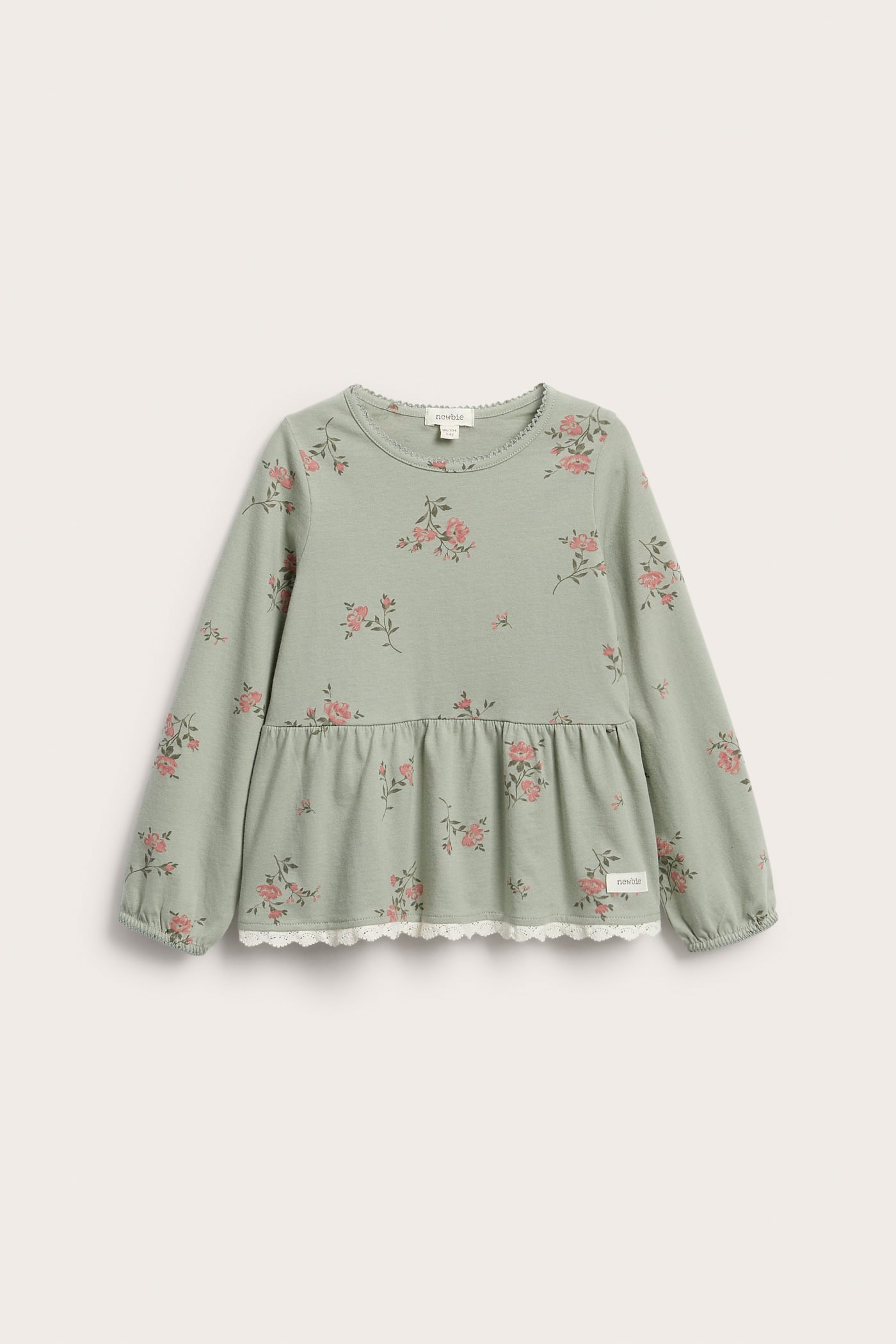 Front view of a kid's green floral long-sleeved cotton peplum top with white lace trim.