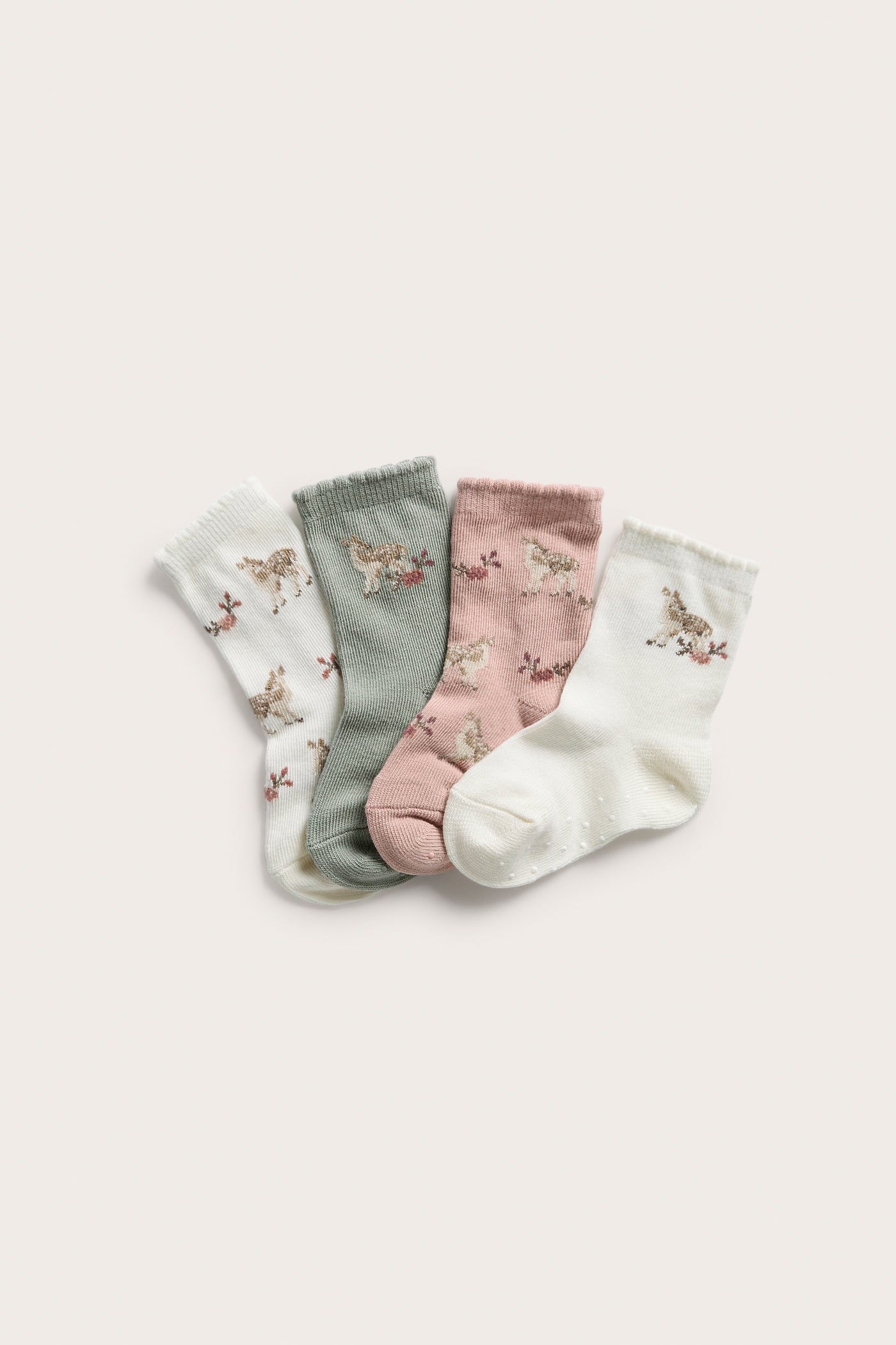 Four pairs of baby socks: off-white, sage green, and pink, all with deer and flower patterns.