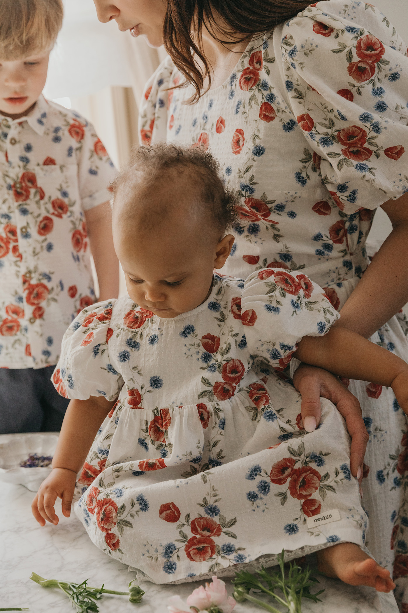 Baby girl in a red floral dress surrounded by her family