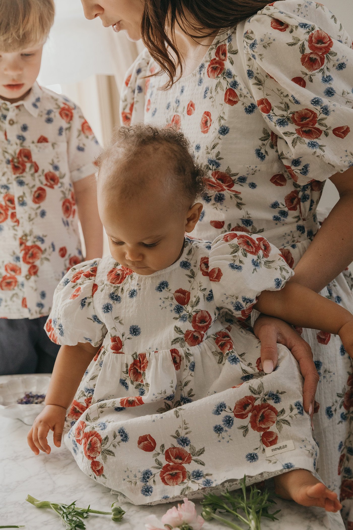 Baby girl in a red floral dress surrounded by her family