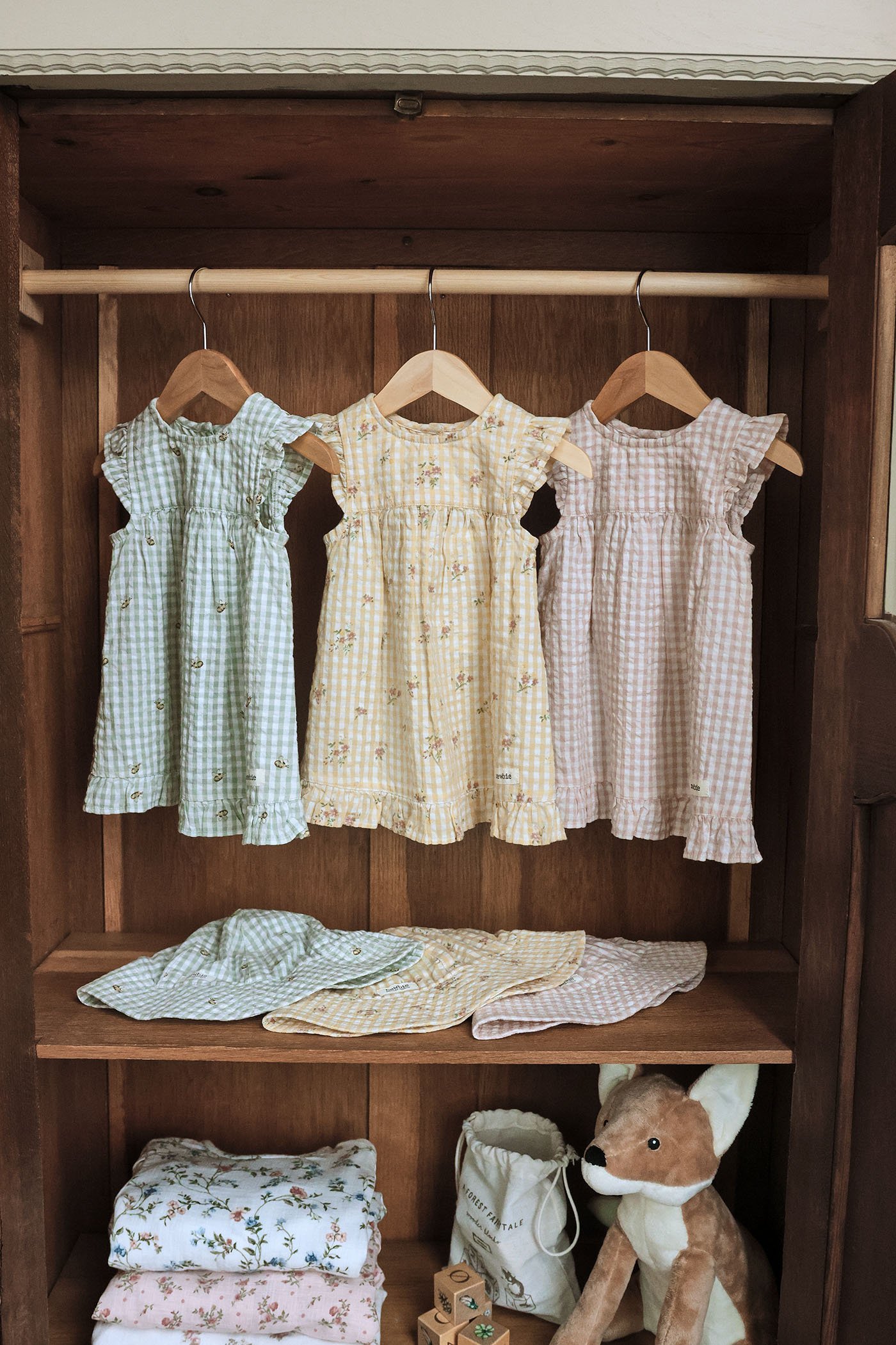 Gingham-patterned, floral dresses on hangers in a wardrobe