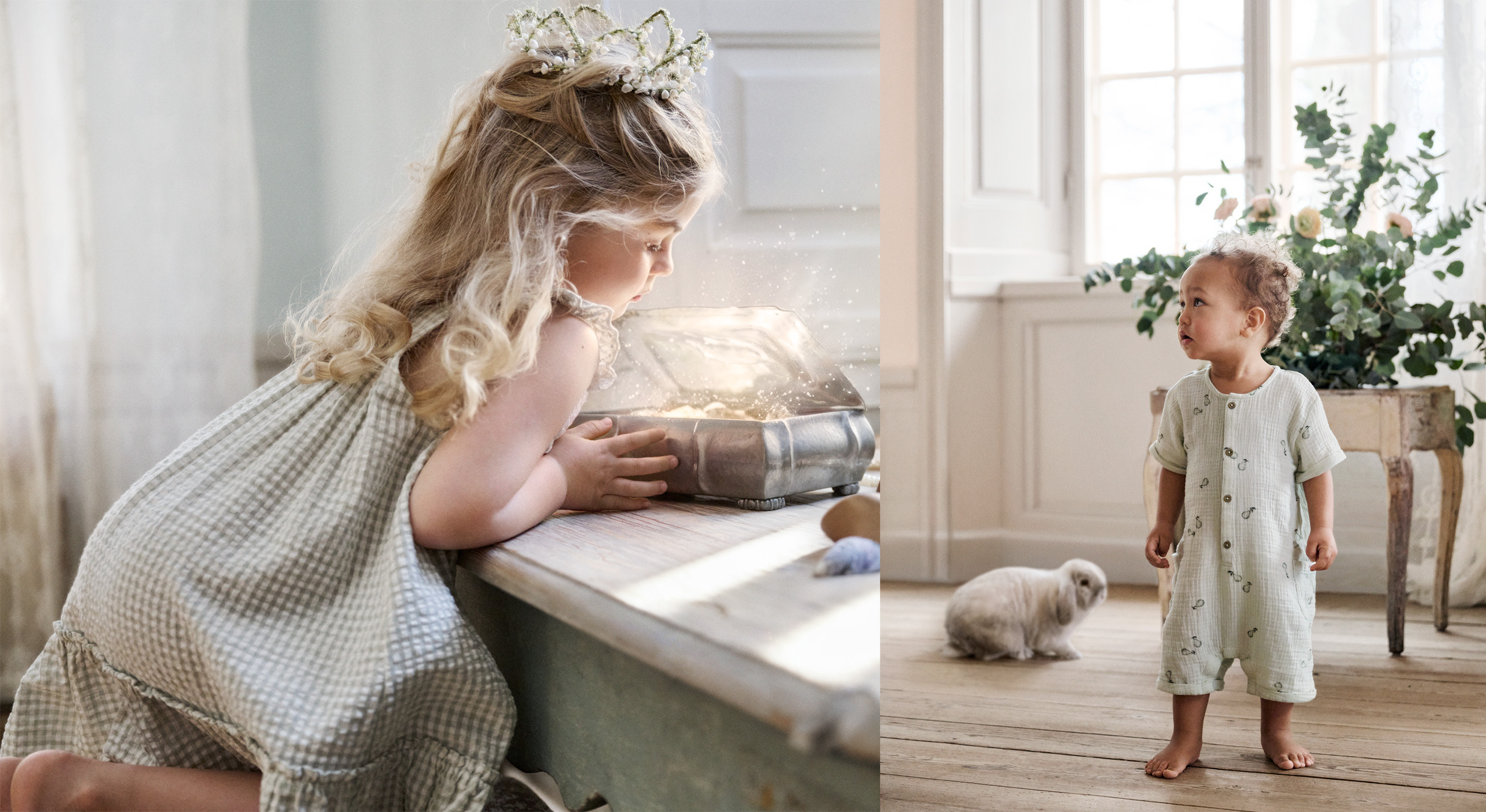 Two young children in soft Newbie outfits indoors, one leaning over a table with a book, the other standing barefoot beside a small rabbit.