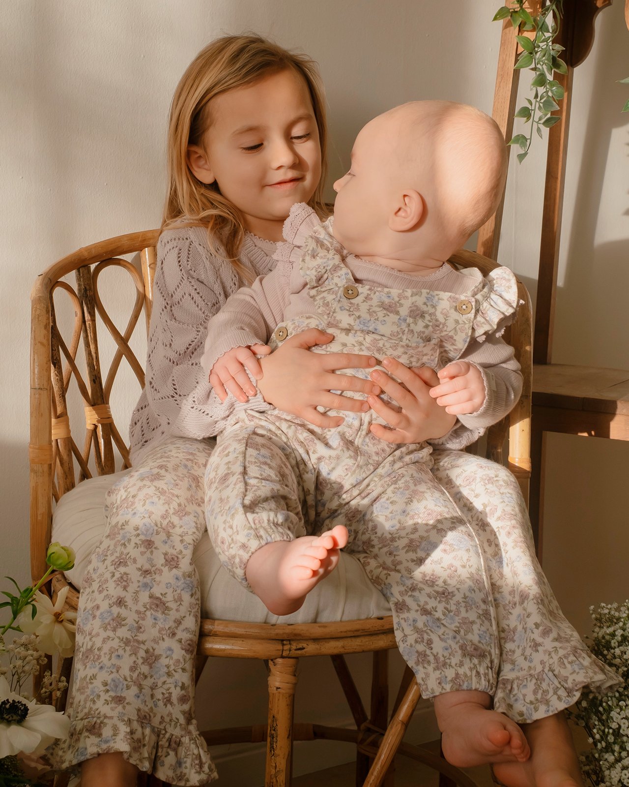 A girl and a baby girl wearing floral clothing