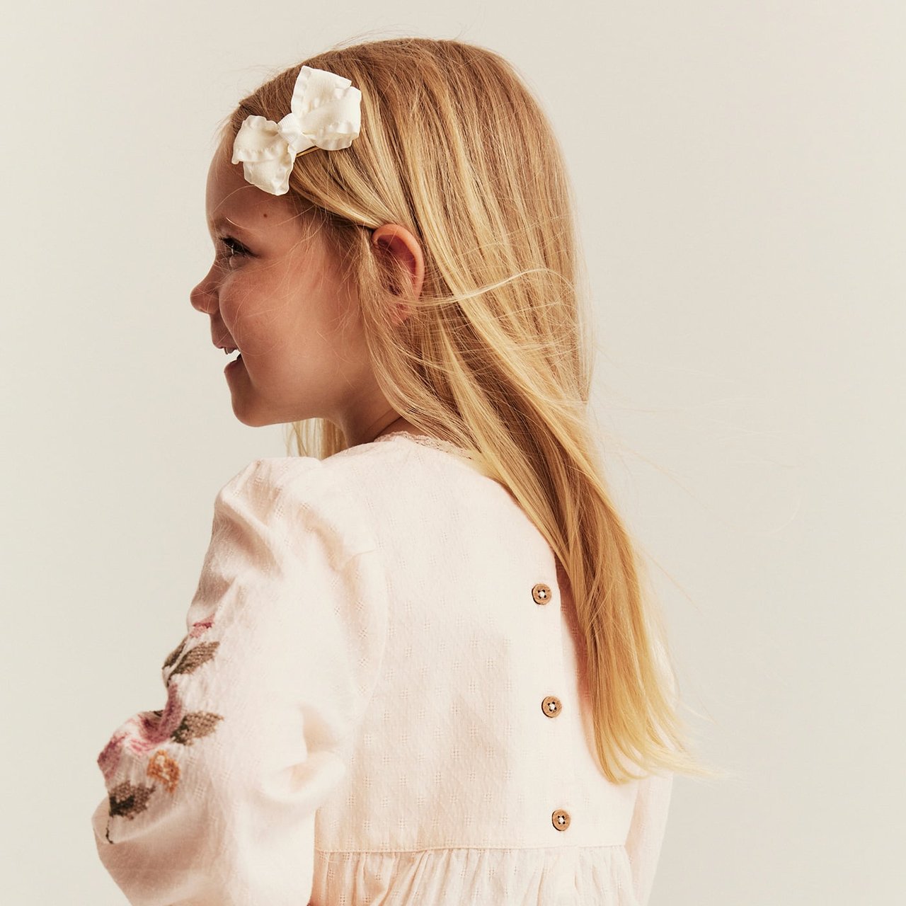 Blouse with embroidered flowers on the sleeves, worn by a little girl.