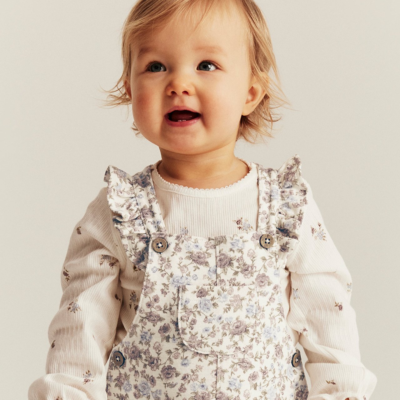 A baby girl wearing a floral dungaree