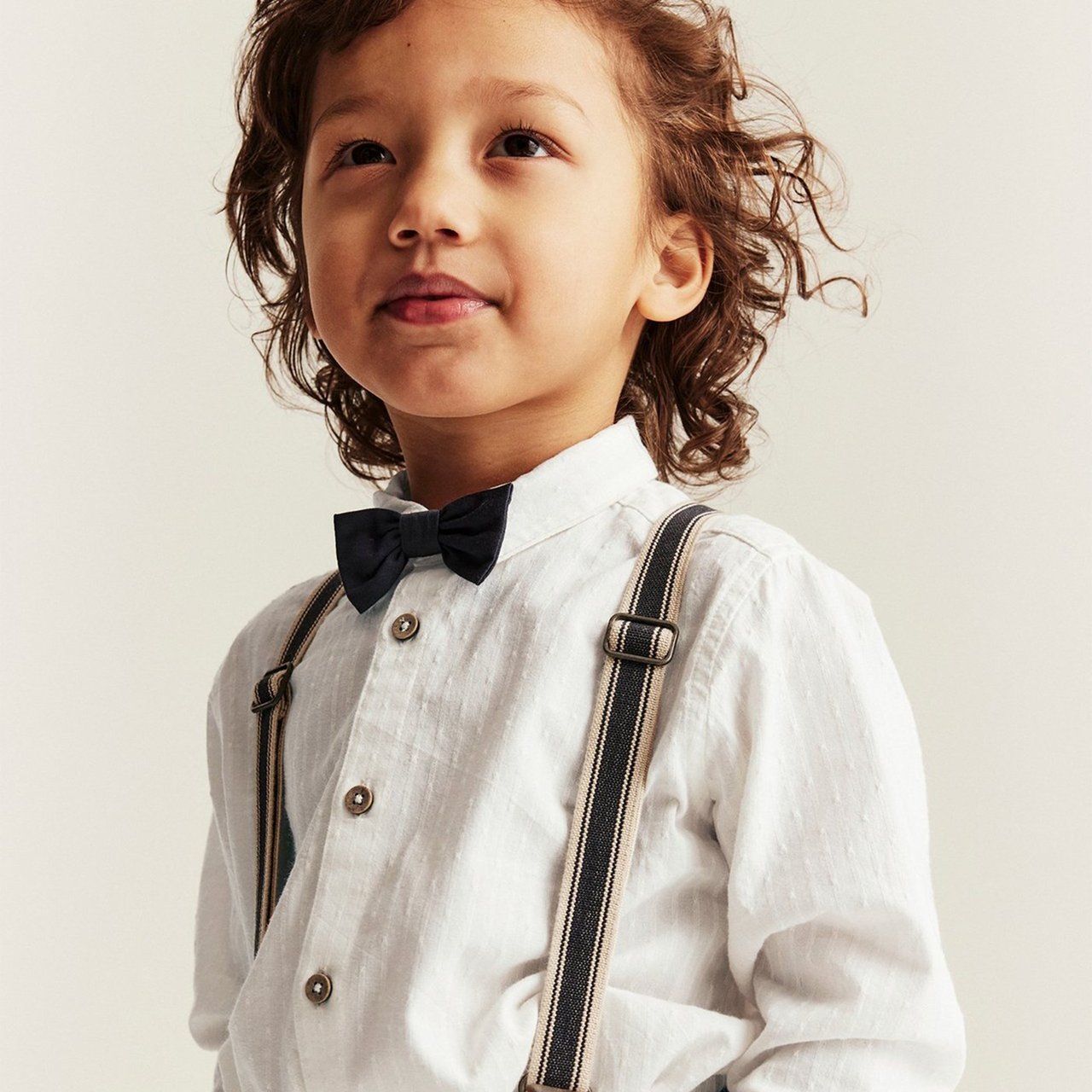 Boy wearing a white shirt with a black bow