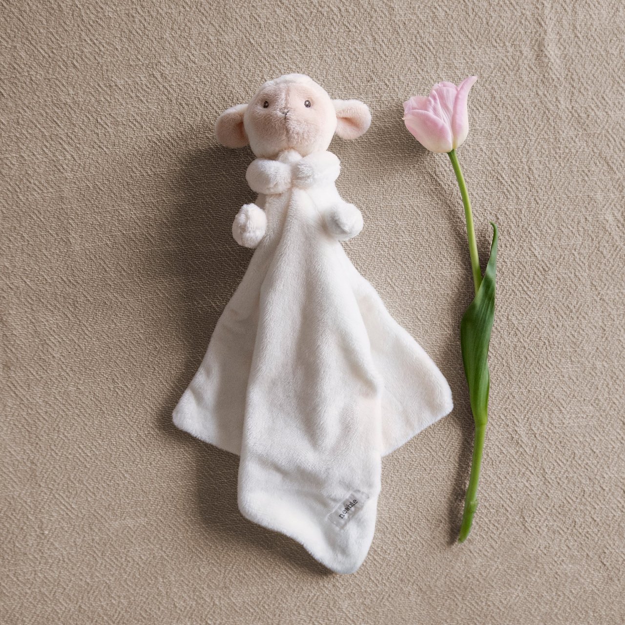 A flat lay of a soft toy blanket and a flower