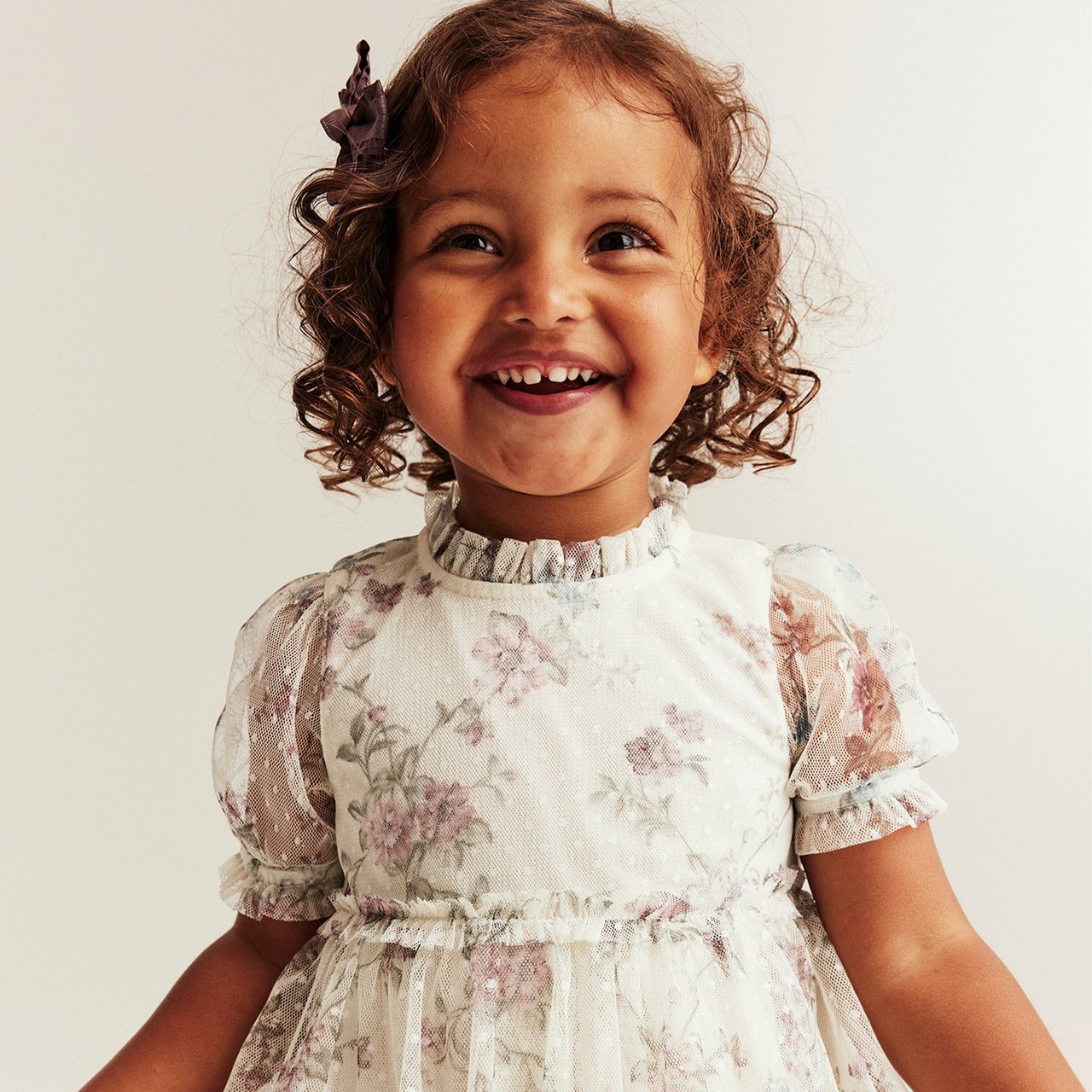 Girl in high neck white dress with pink flower print with lace details