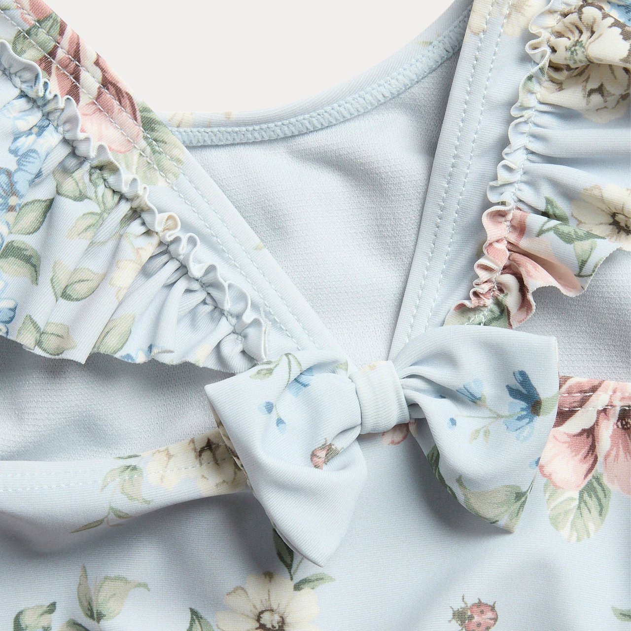 A flat lay of a blue swimsuit with a pattern of pink flowers on it