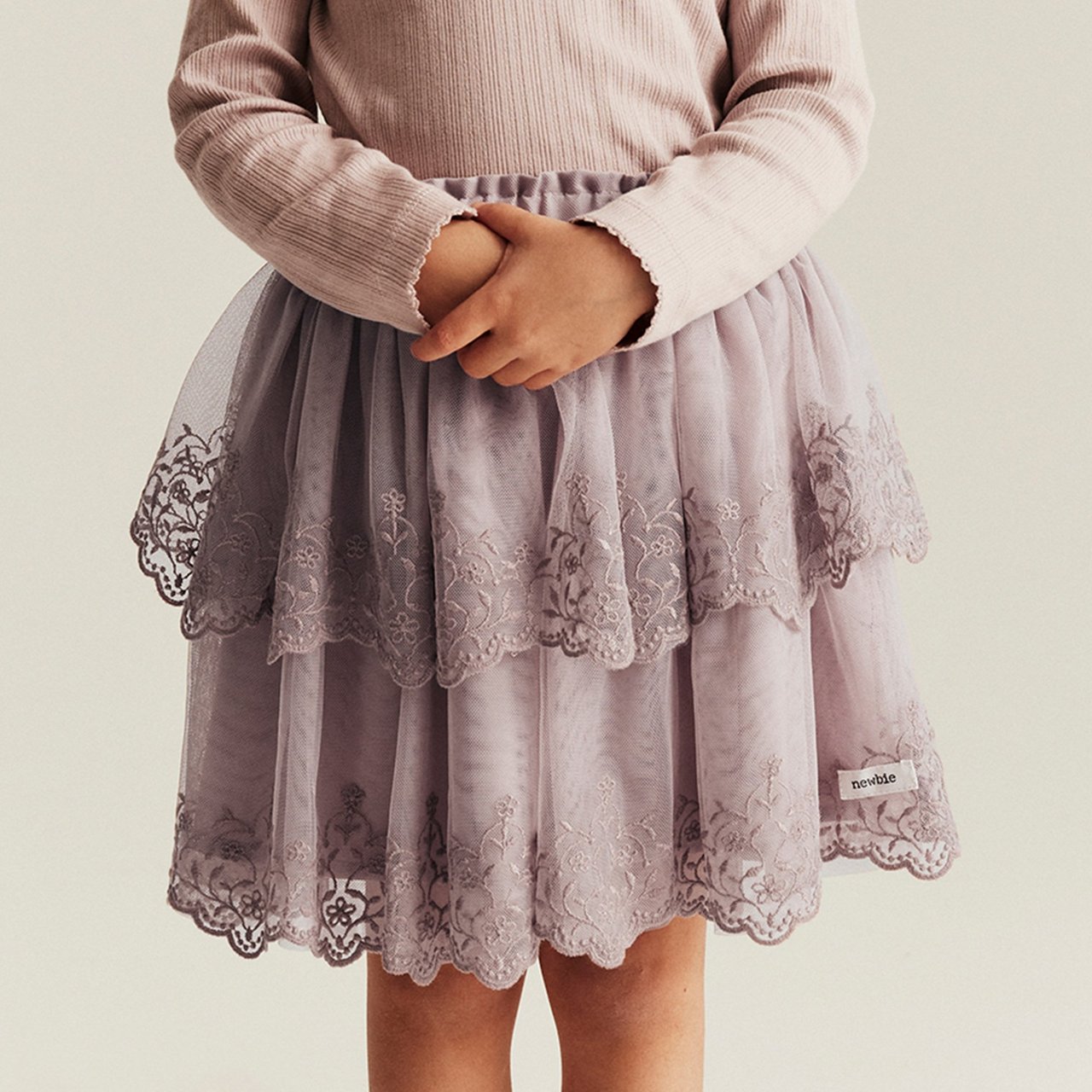 Ein Mädchen, das einen lilafarbenen Chiffon- und Spitzrock trägt.