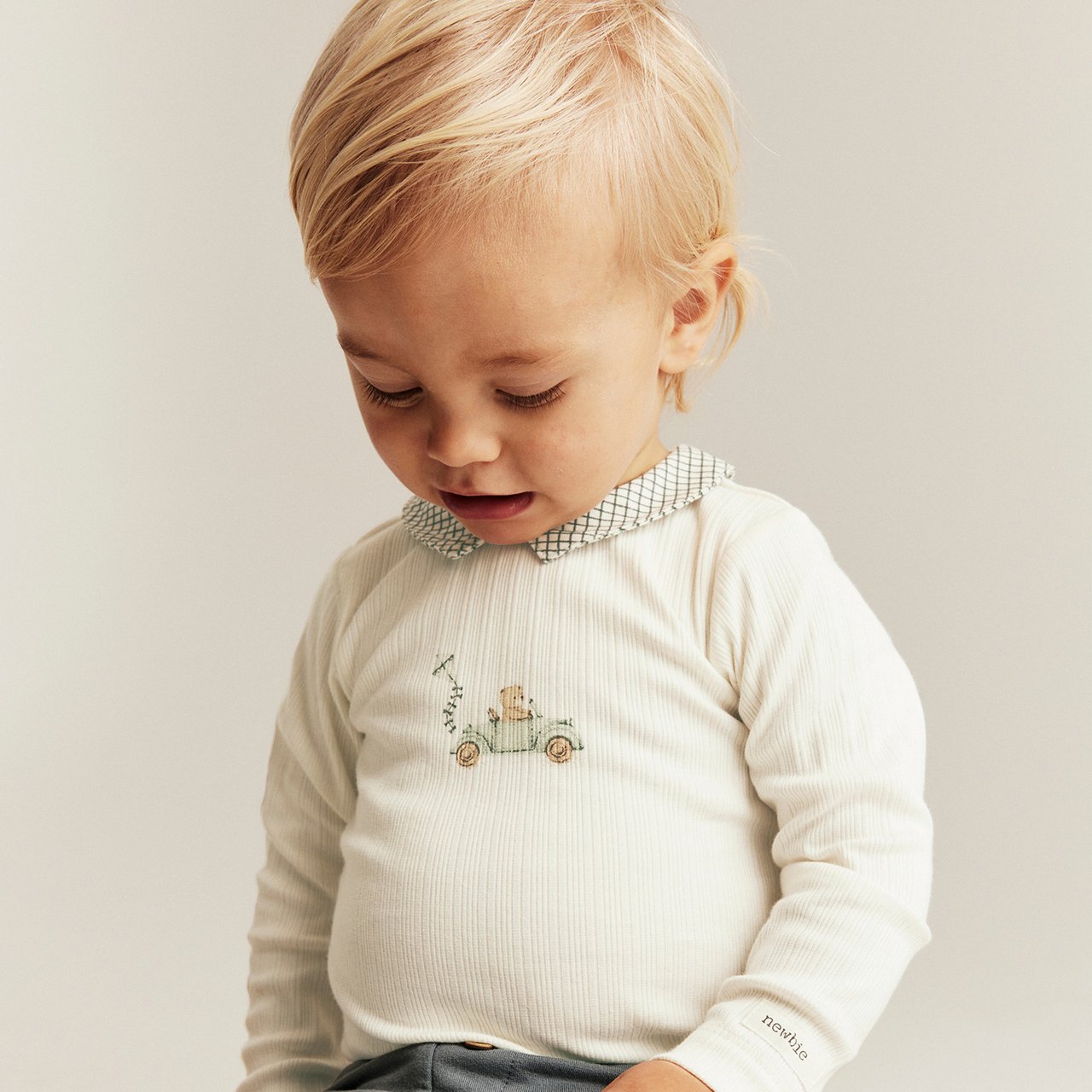 Baby trägt einen weißen Body mit Rüschen.