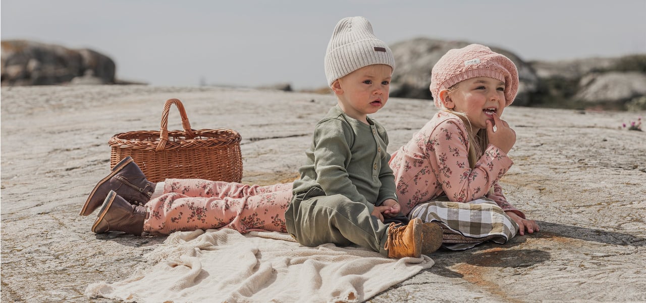 Kids on a picnic blanket on a cliff by the sea