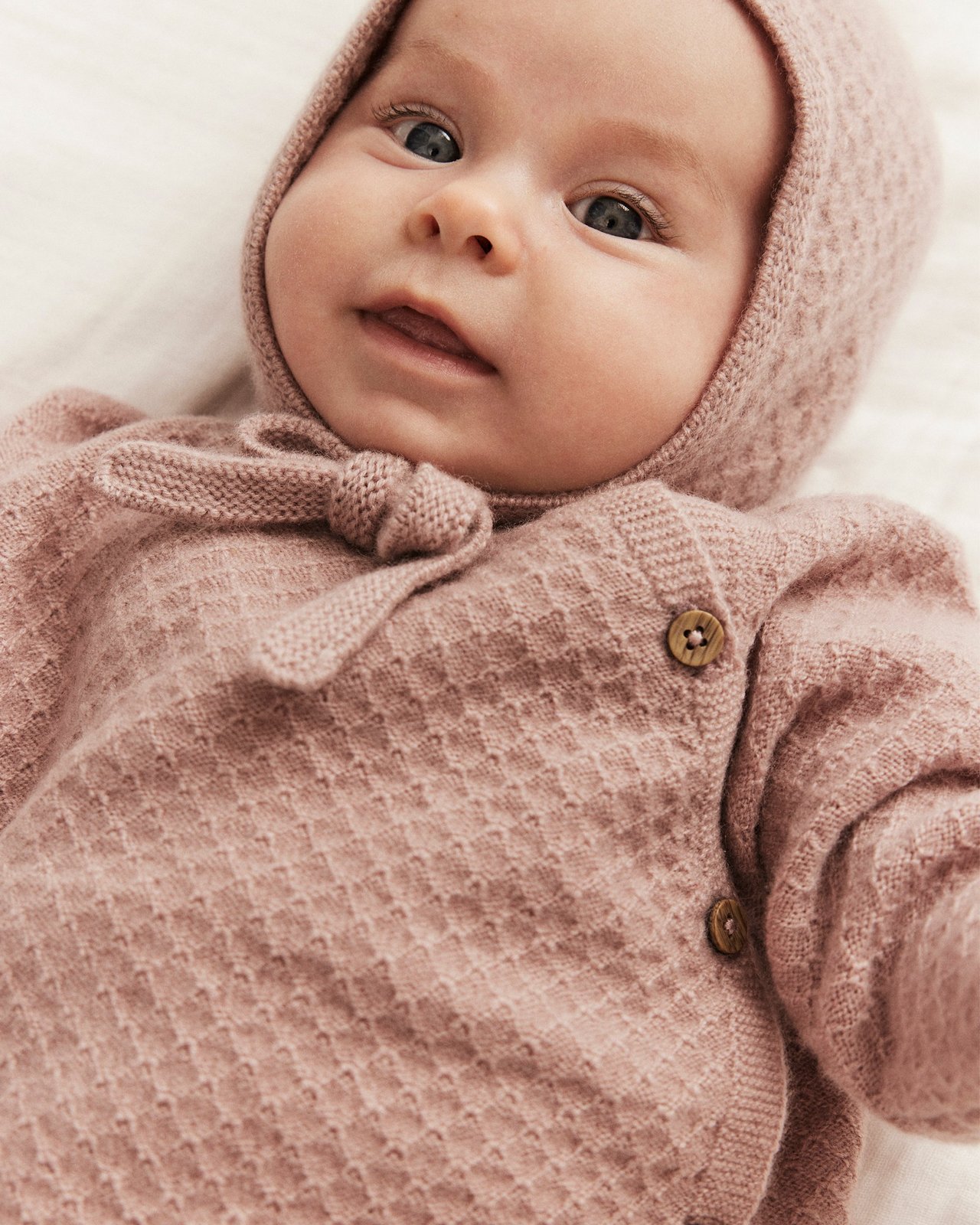 Baby wearing a cashmere cardigan and bonnet