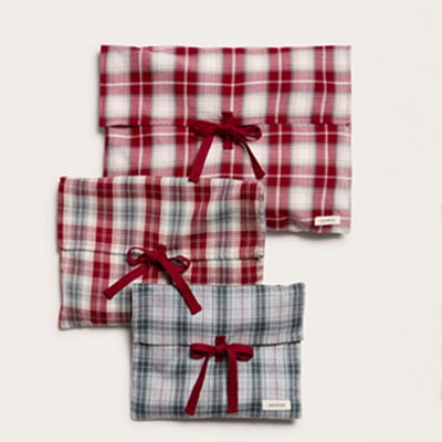 Plaid fabric gift bags with decorative ribbon ties in seasonal red and blue tones.