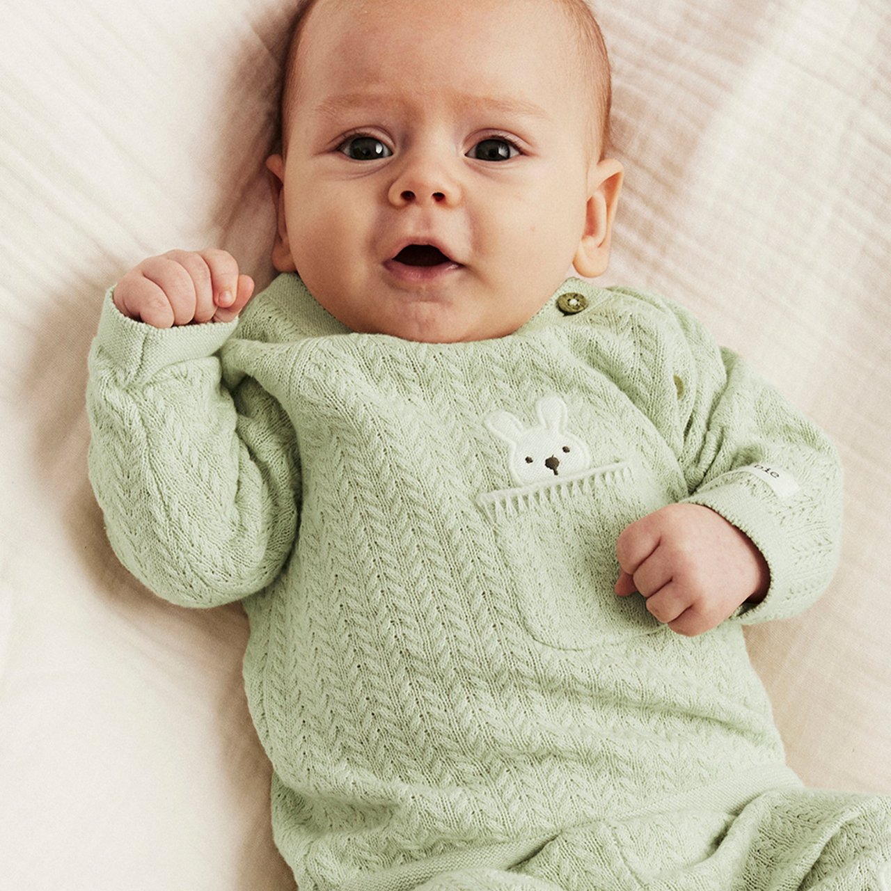 Baby in green bodysuit with a rabbit on it