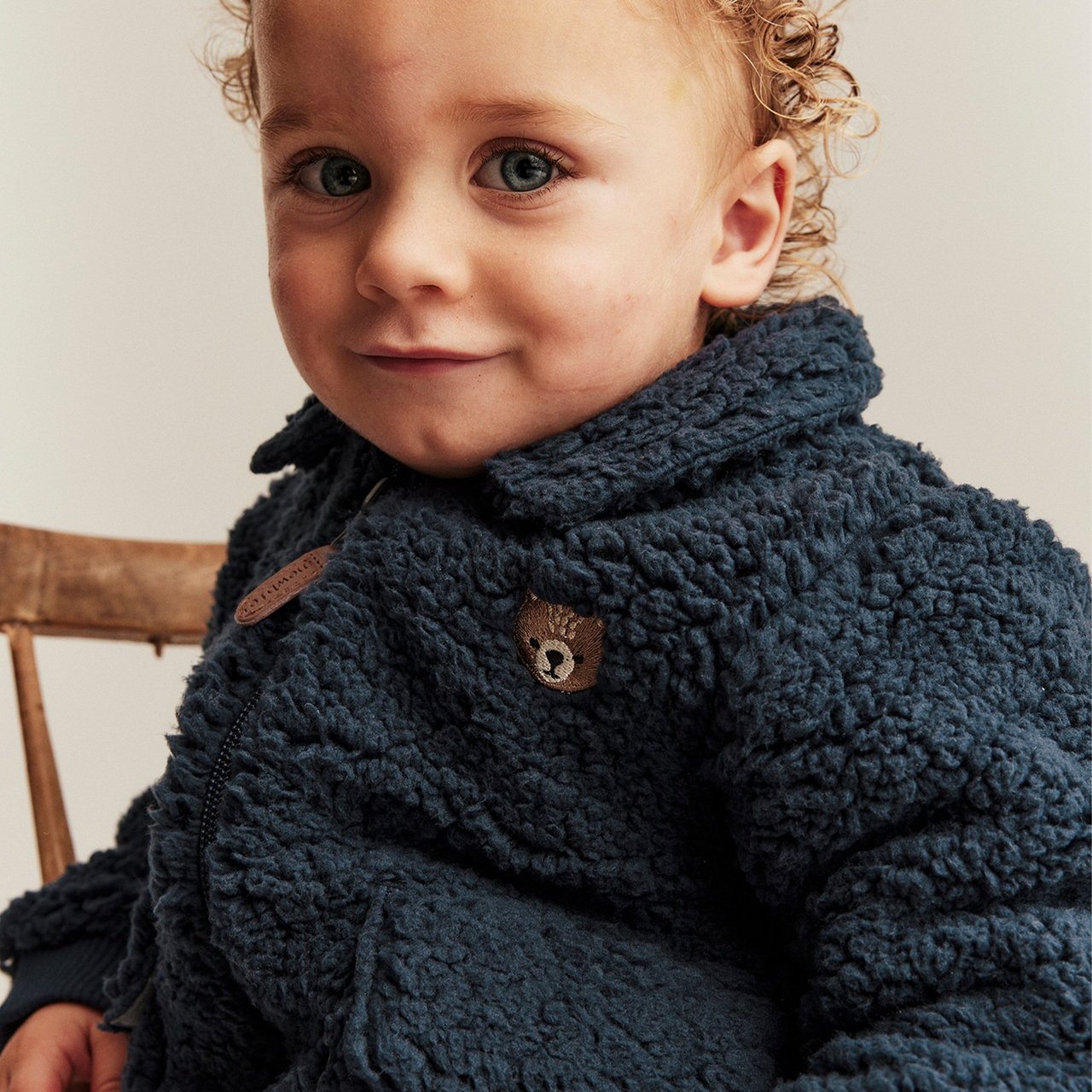 Baby boy in blue pile jacket with a teddybear on it
