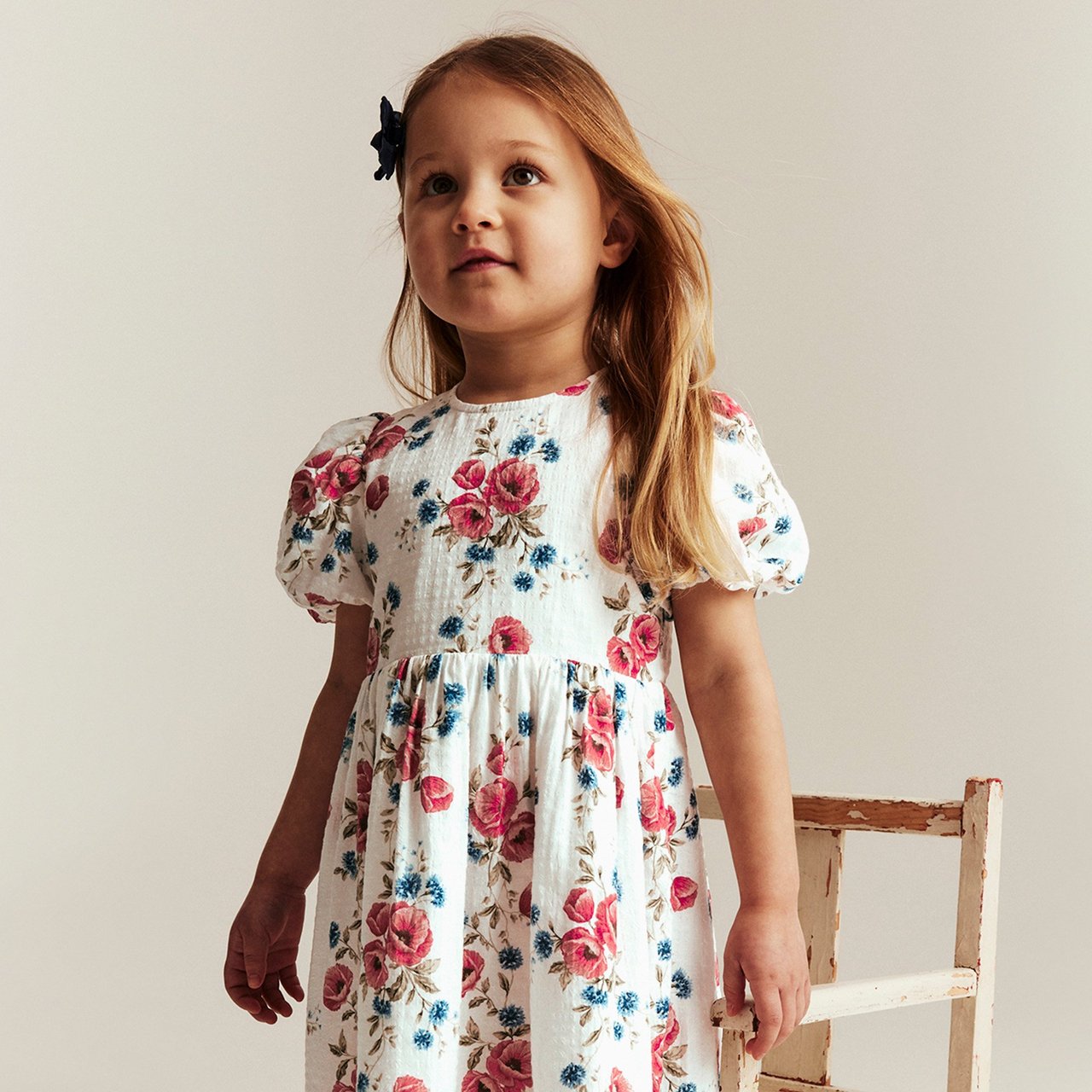 Girl in a red floral dress staring into the distance