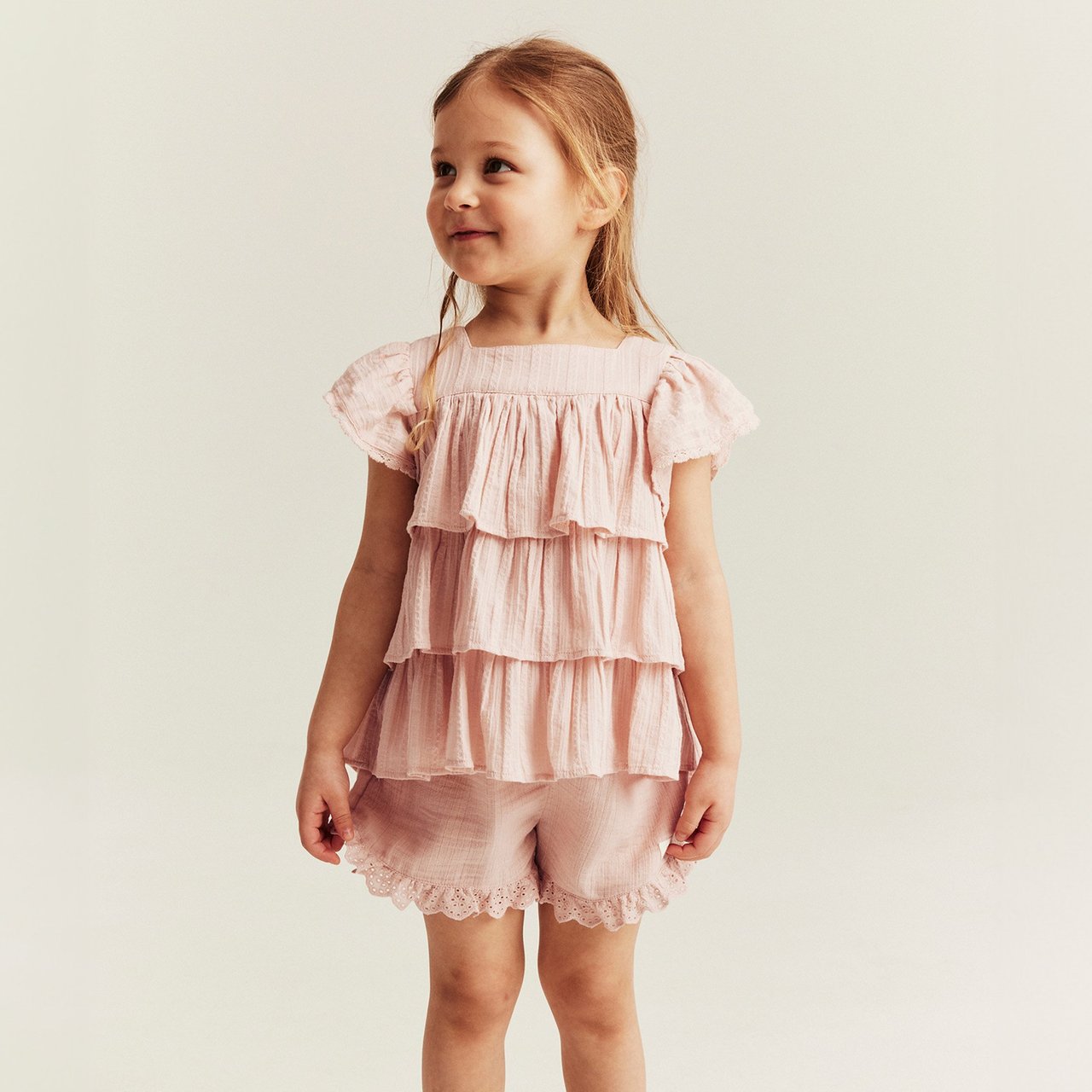 Girl wearing a light pink tiered top with matching lace‑trimmed shorts