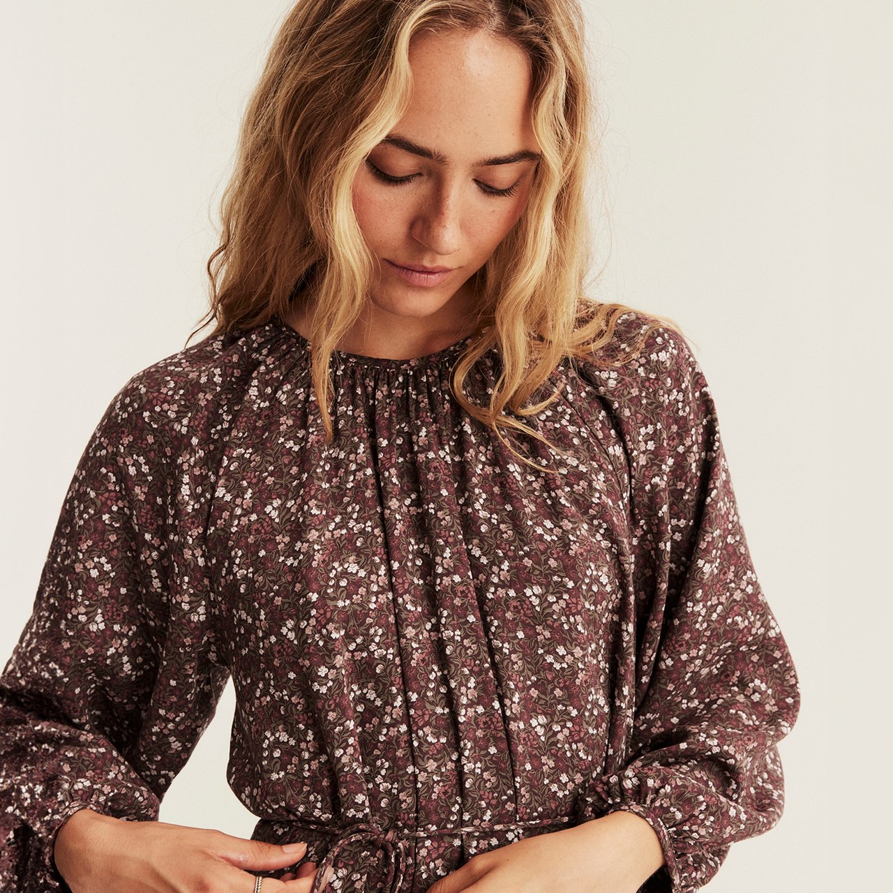 Burgundy long-sleeved dress with small floral print, gathered neckline and tie waist detail.