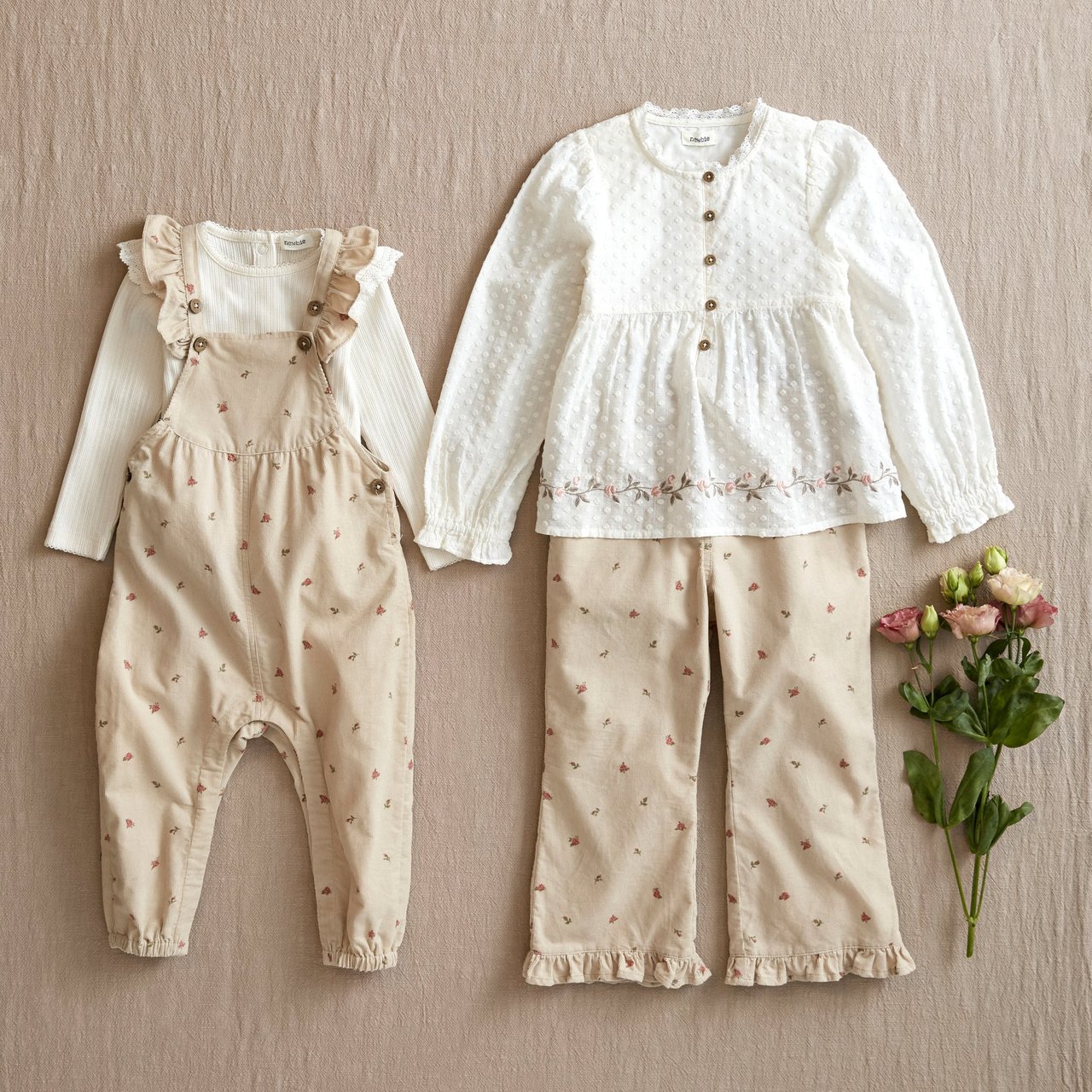 A flat lay of sibling matching outfits in beige and white tones