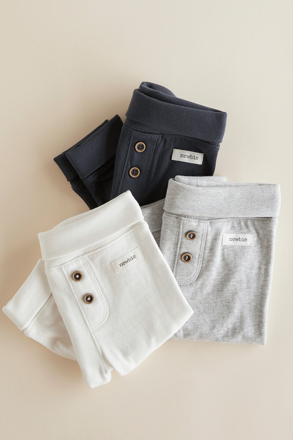 Gefaltete gerippte Babyleggings in Dunkelblau, Hellgrau und Off-White mit Knopfleiste.