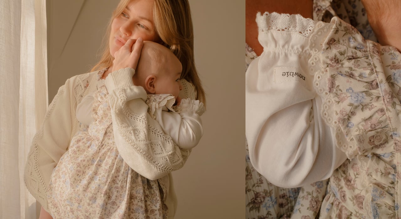 A woman holding a child, wearing a white floral patterned blouse