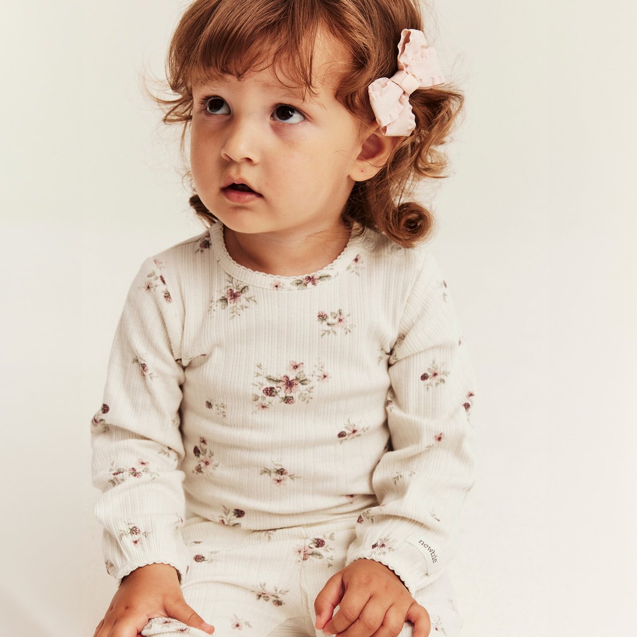 Cream ribbed long-sleeved top with small floral print and picot trim for babies.