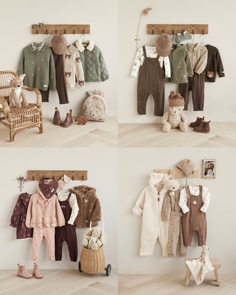 Baby-Outfits in Grün, Braun, Rosa und Beige an Wandhaken mit passenden Mützen, Schuhen und Kuscheltieren.