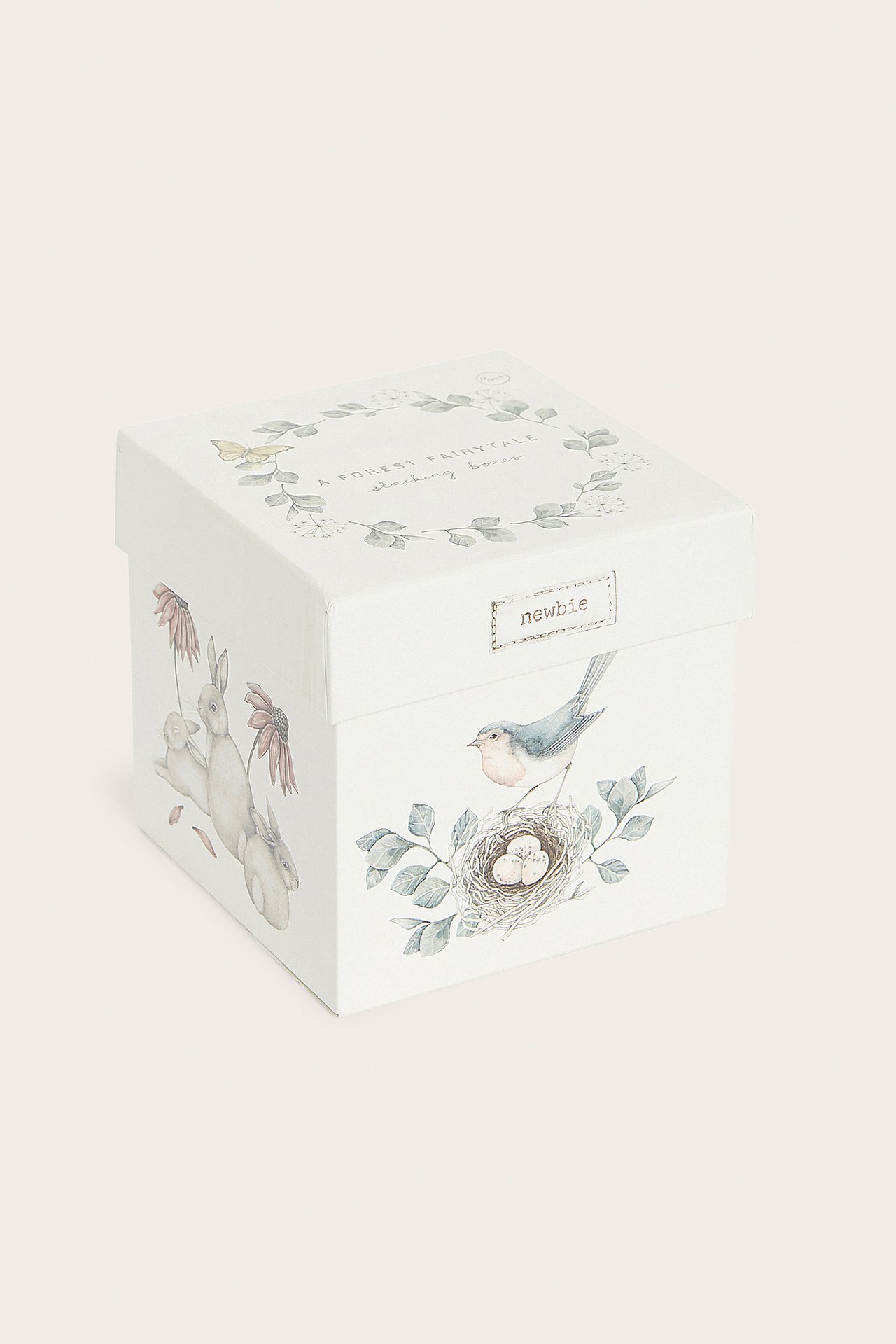 Vorderansicht einer cremefarbenen, gemusterten Papierbox mit Stapelklötzen, verziert mit Hasen- und Vogelillustrationen.