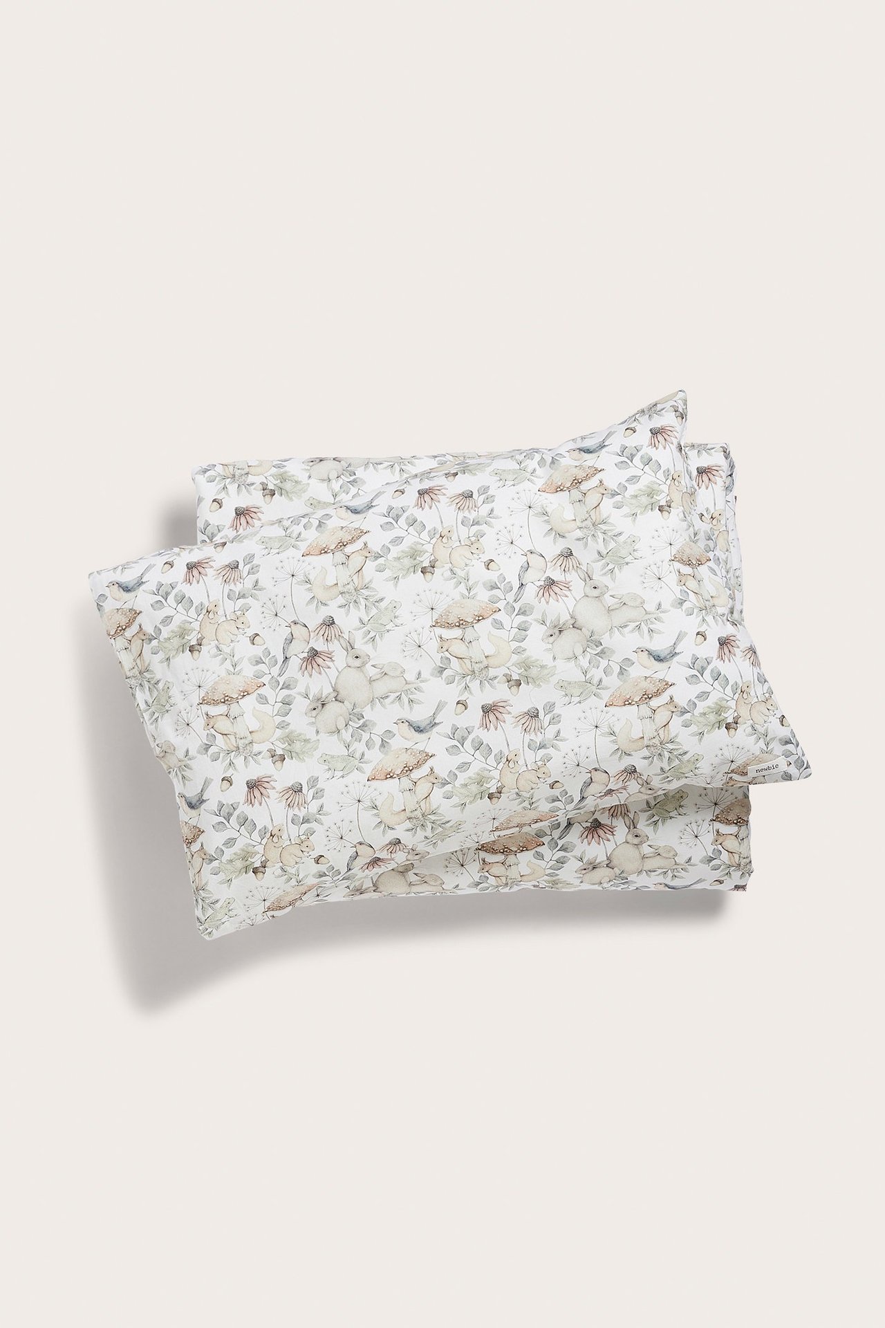 Draufsicht auf ein gefaltetes hellbeiges Baumwoll-Bettwäscheset mit Waldtiermuster.