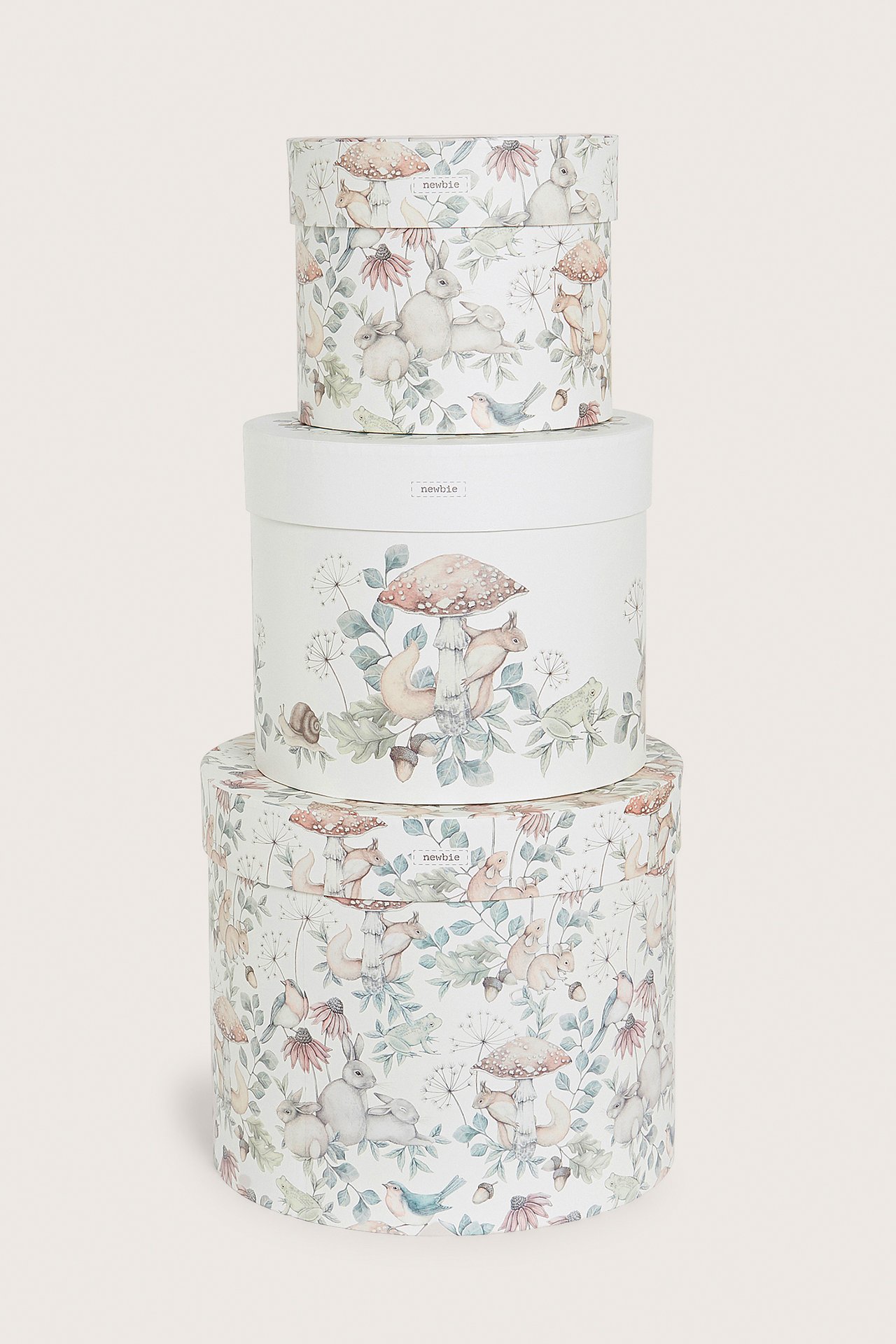Front view of three round beige patterned paper storage boxes, stacked, featuring a nature print with animals and mushrooms.