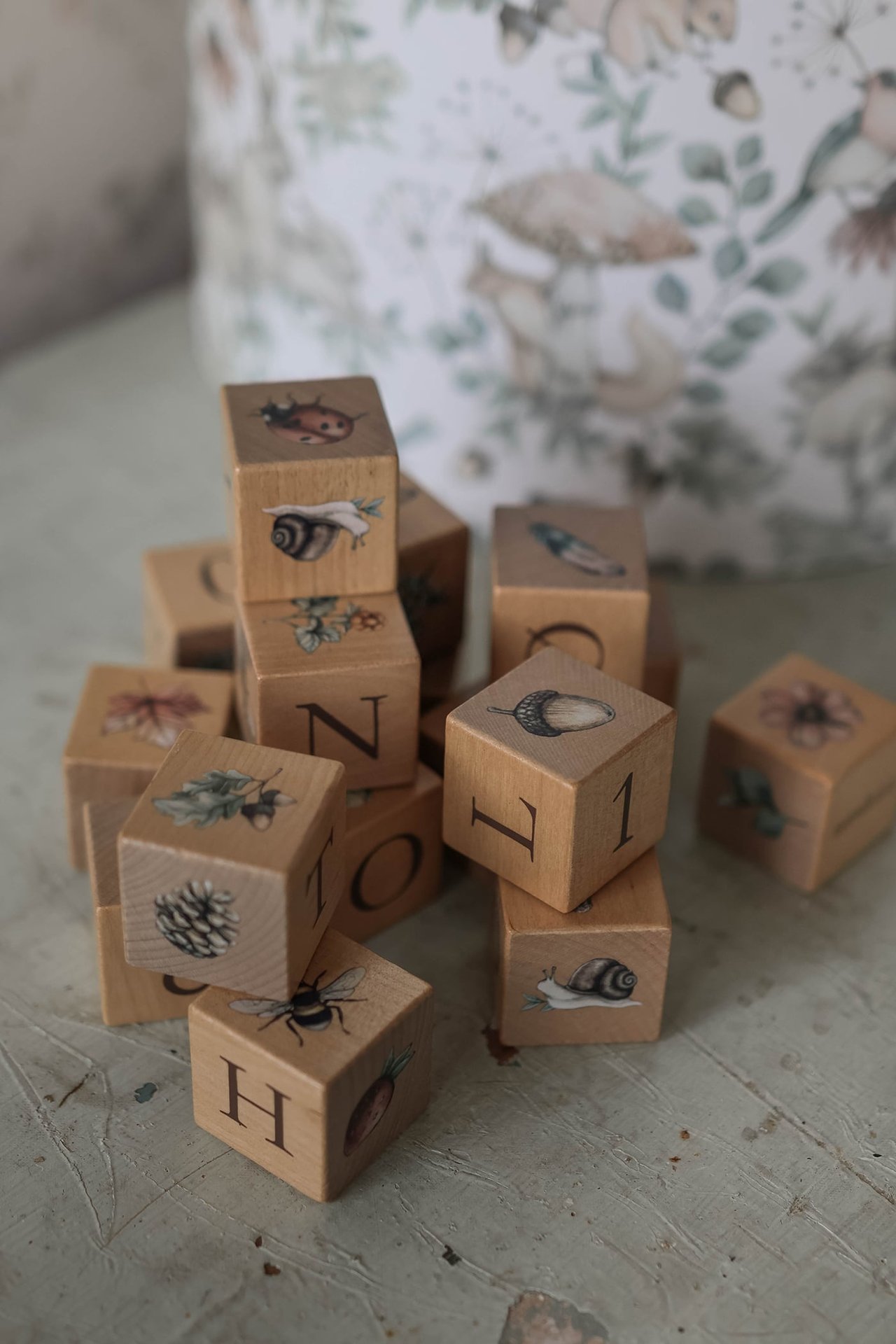 Nahaufnahme von naturbelassenen Holzklötzen mit Buchstaben, Zahlen und verschiedenen Tier- und Naturmotiven.