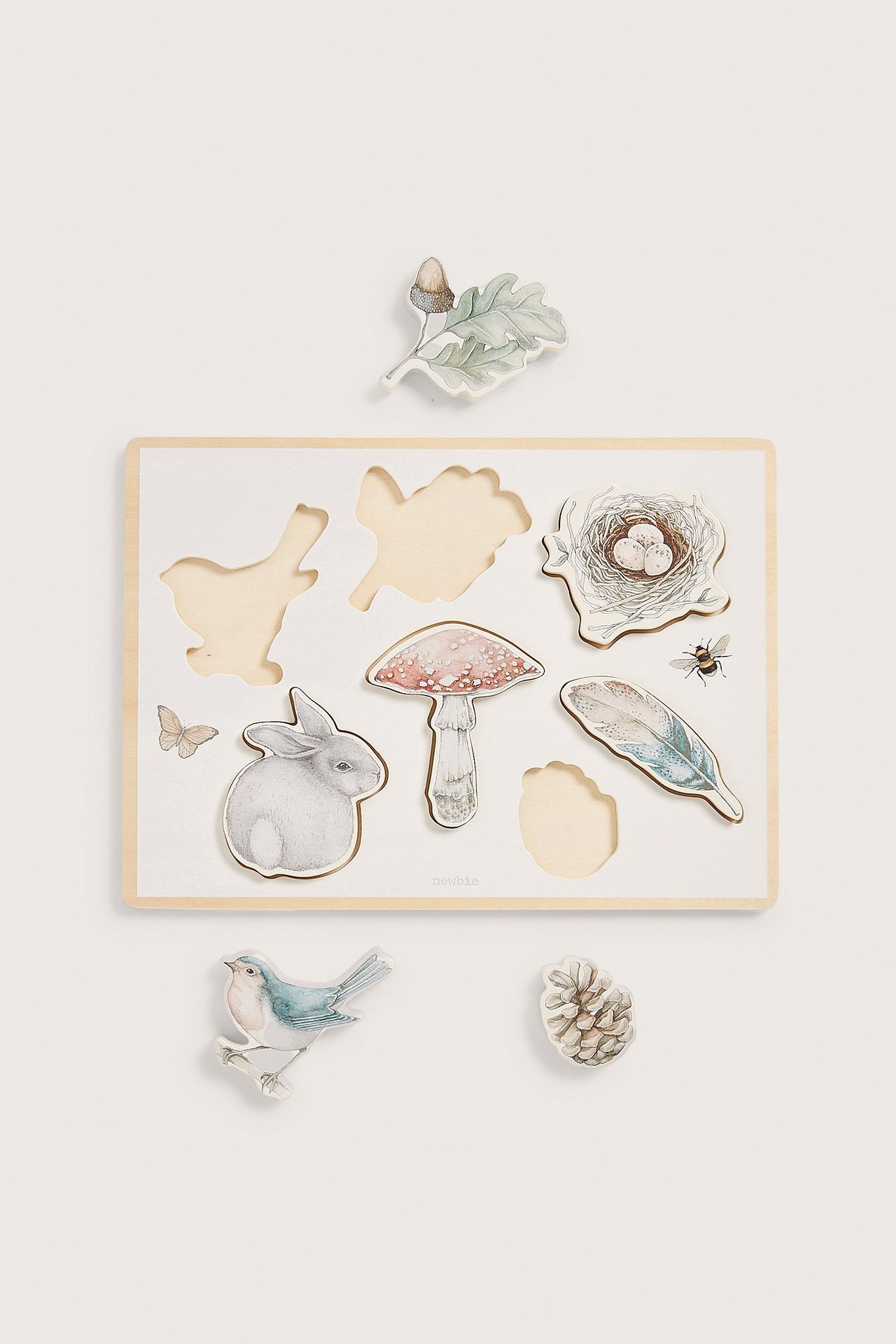 Draufsicht auf ein cremefarbenes Holzpuzzle mit Waldtier- und Naturmotiven, sieben Teile.