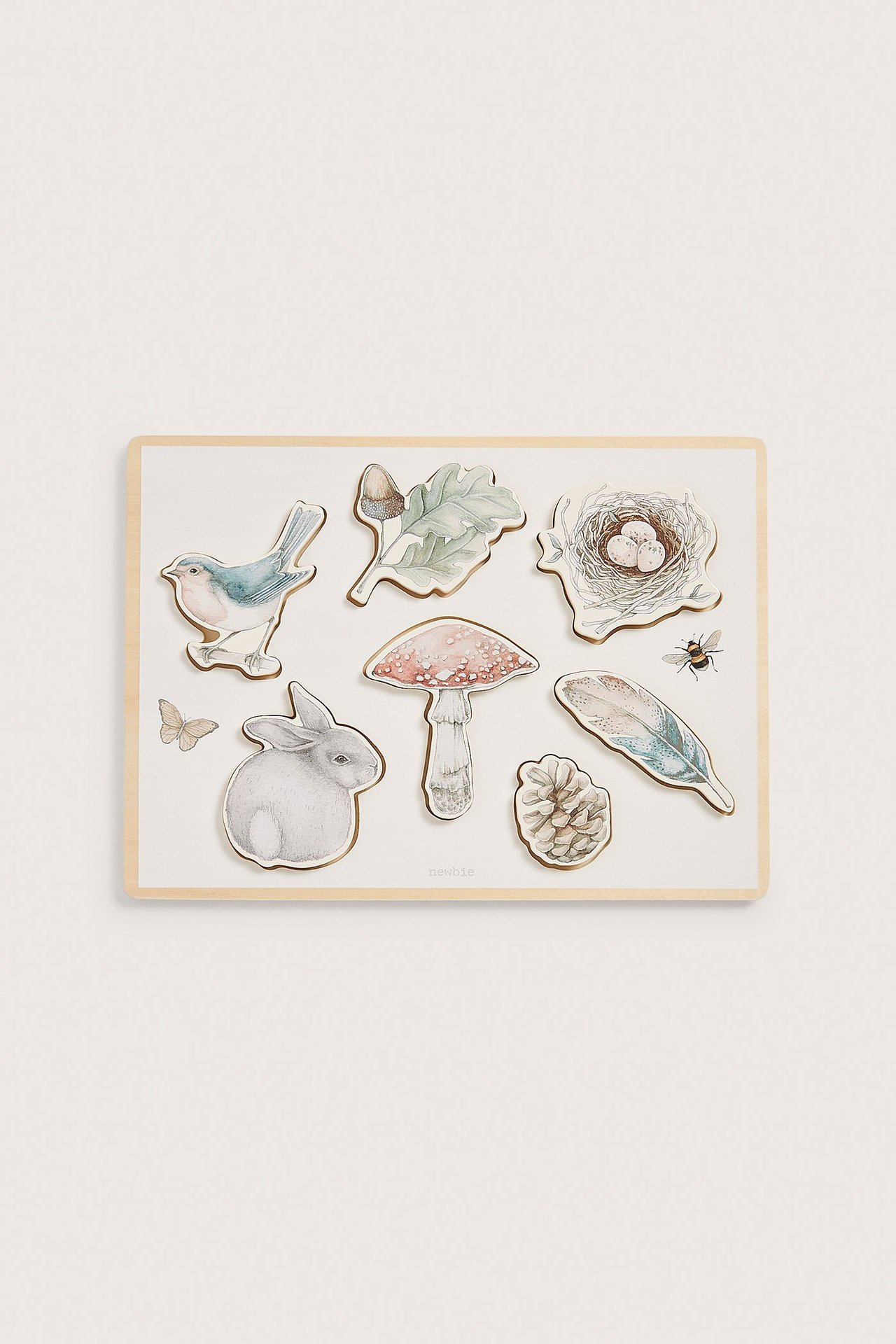Vorderansicht eines cremefarbenen Holzpuzzles mit sieben Waldtier- und Naturmotivteilen.