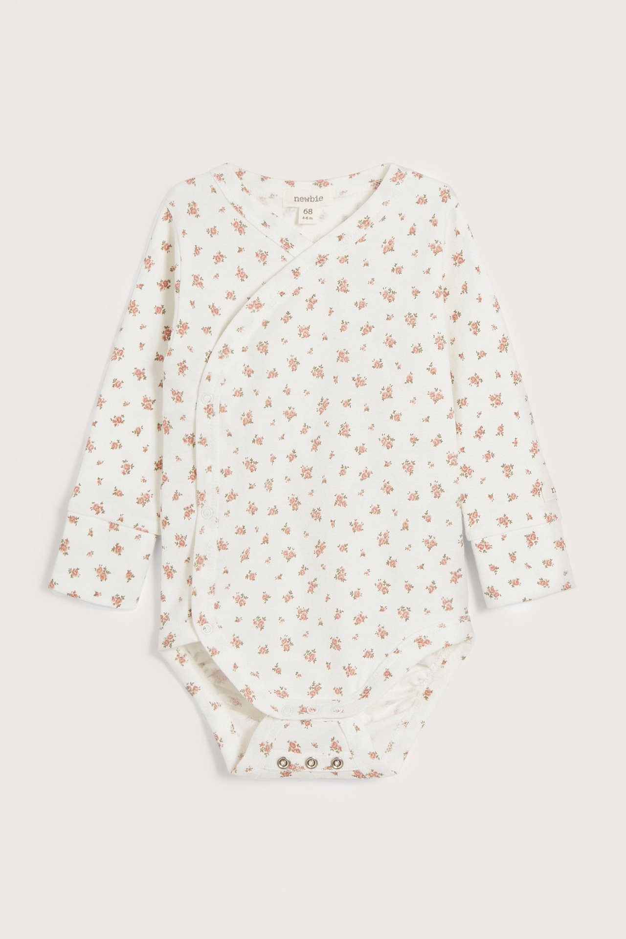 Front view of an off-white baby wrap-around cotton bodysuit with a small floral pattern and snap buttons.