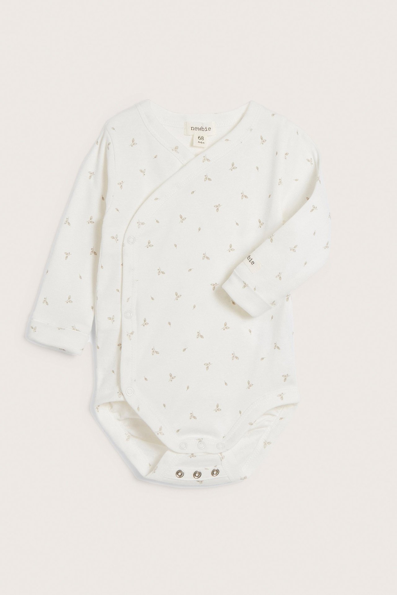Vorderansicht eines beigen gerippten Baby-Wickelbodys mit kleinem Blattmuster und Druckknöpfen.