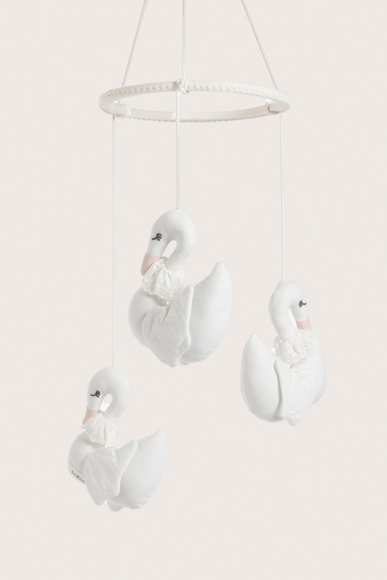 Front view: Off-white cotton hanging mobile with three plush swans, lace details, and a top ring.