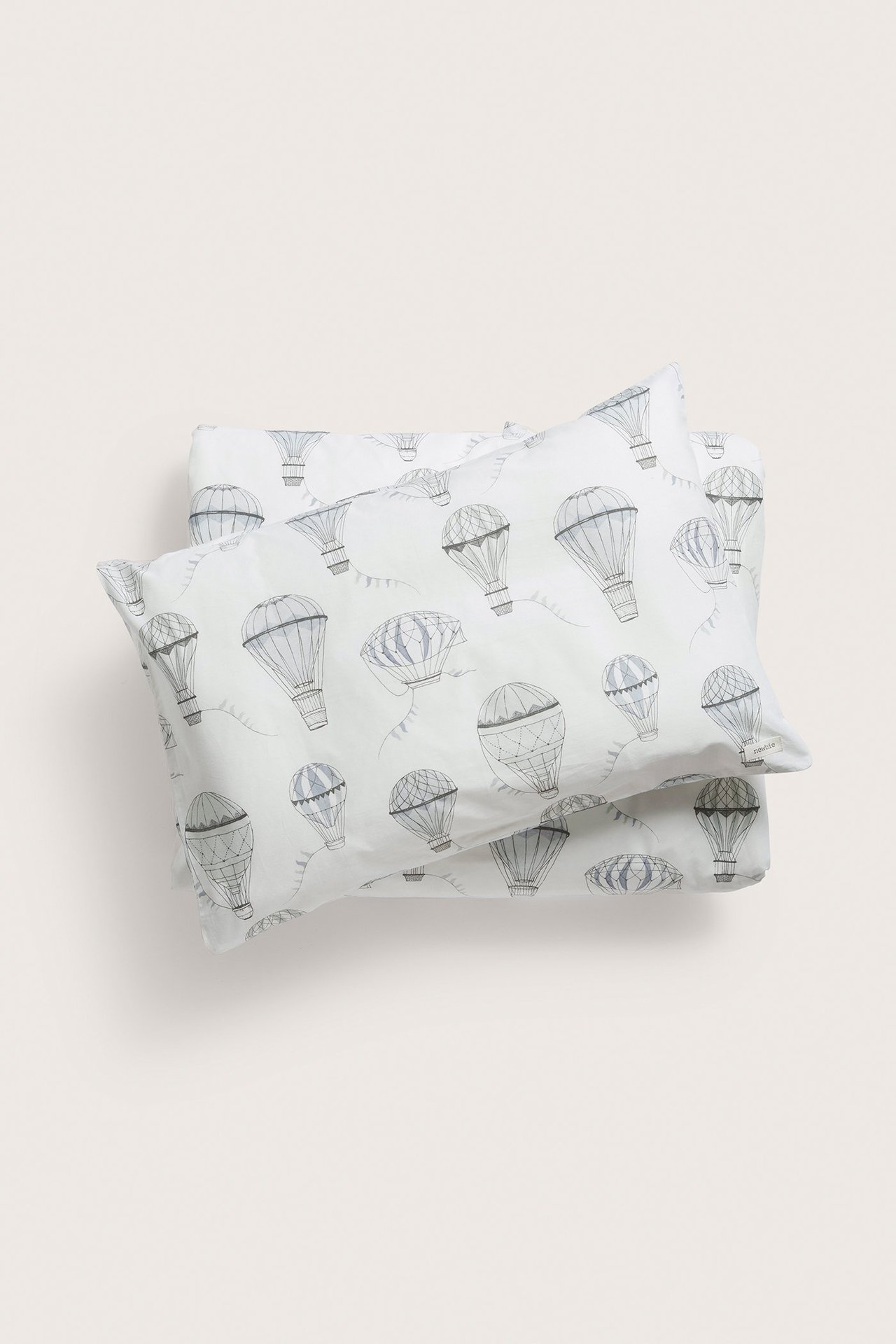 Draufsicht auf ein cremefarbenes Baumwoll-Bettwäscheset mit grauem Heißluftballonmuster.