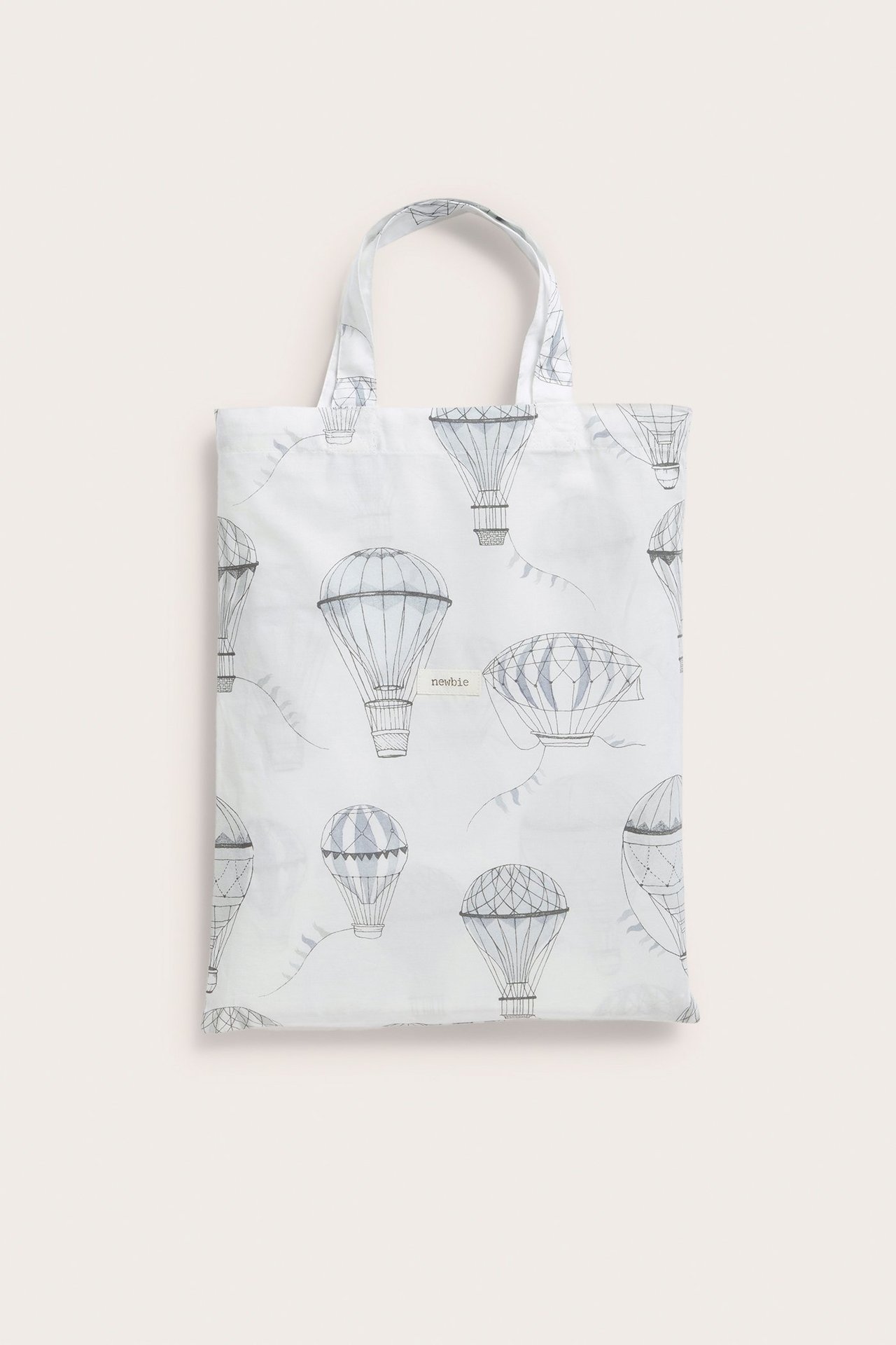 Vorderansicht einer cremefarbenen Baumwolltasche mit grauem Heißluftballonmuster und 'Newbie'-Etikett.