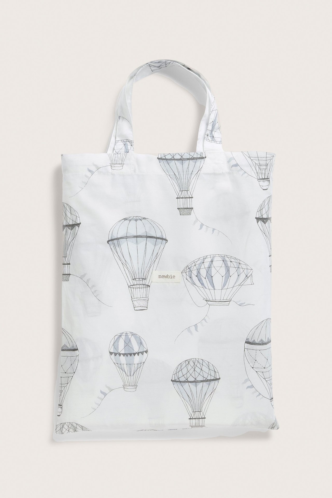 Vorderansicht einer cremefarbenen Baumwolltasche mit grauem Heißluftballonmuster, die ein Bettwäscheset enthält.