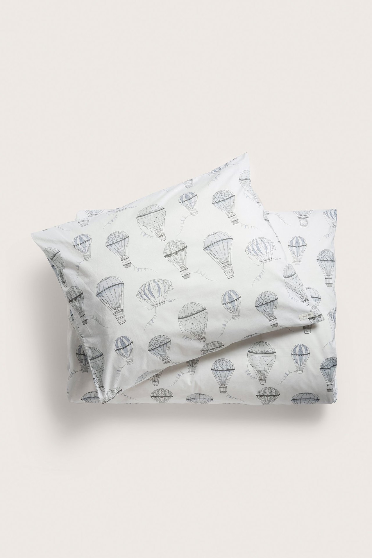 Draufsicht auf ein off-weißes Baumwoll-Bettwäscheset mit grauem Heißluftballon-Muster.