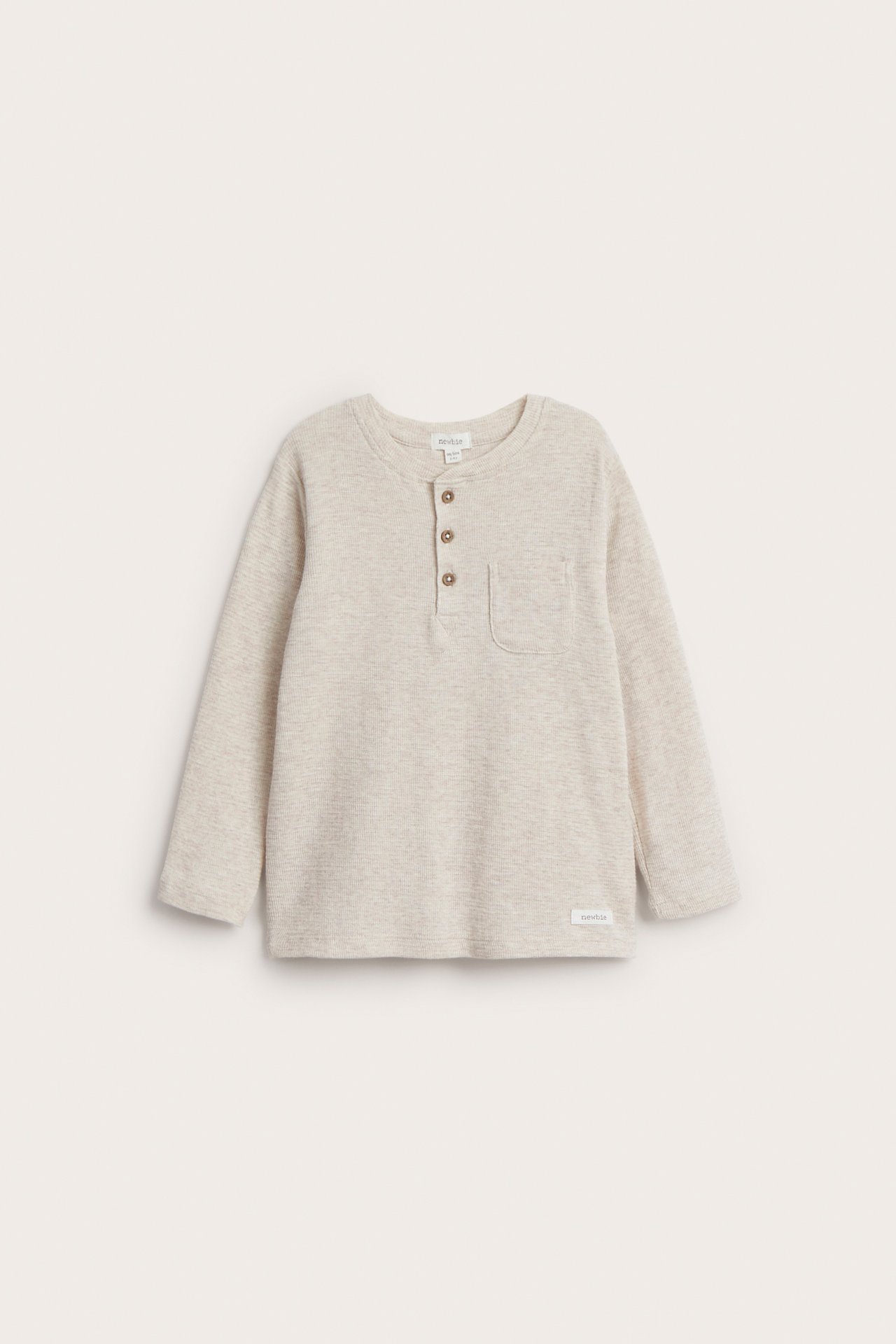 Vorderansicht eines hellbeigen strukturierten Langarm-Henley-Shirts für Kinder mit drei Knöpfen und Brusttasche.