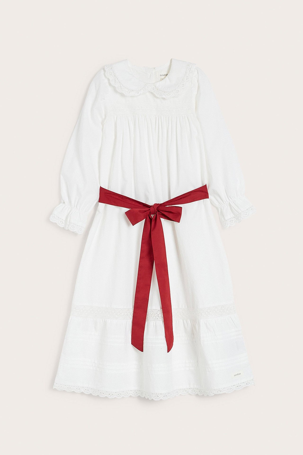 Vorderansicht eines cremeweißen Lucia-Kleides aus Baumwolle für Kinder mit Spitzenkragen und rotem Bindegürtel.