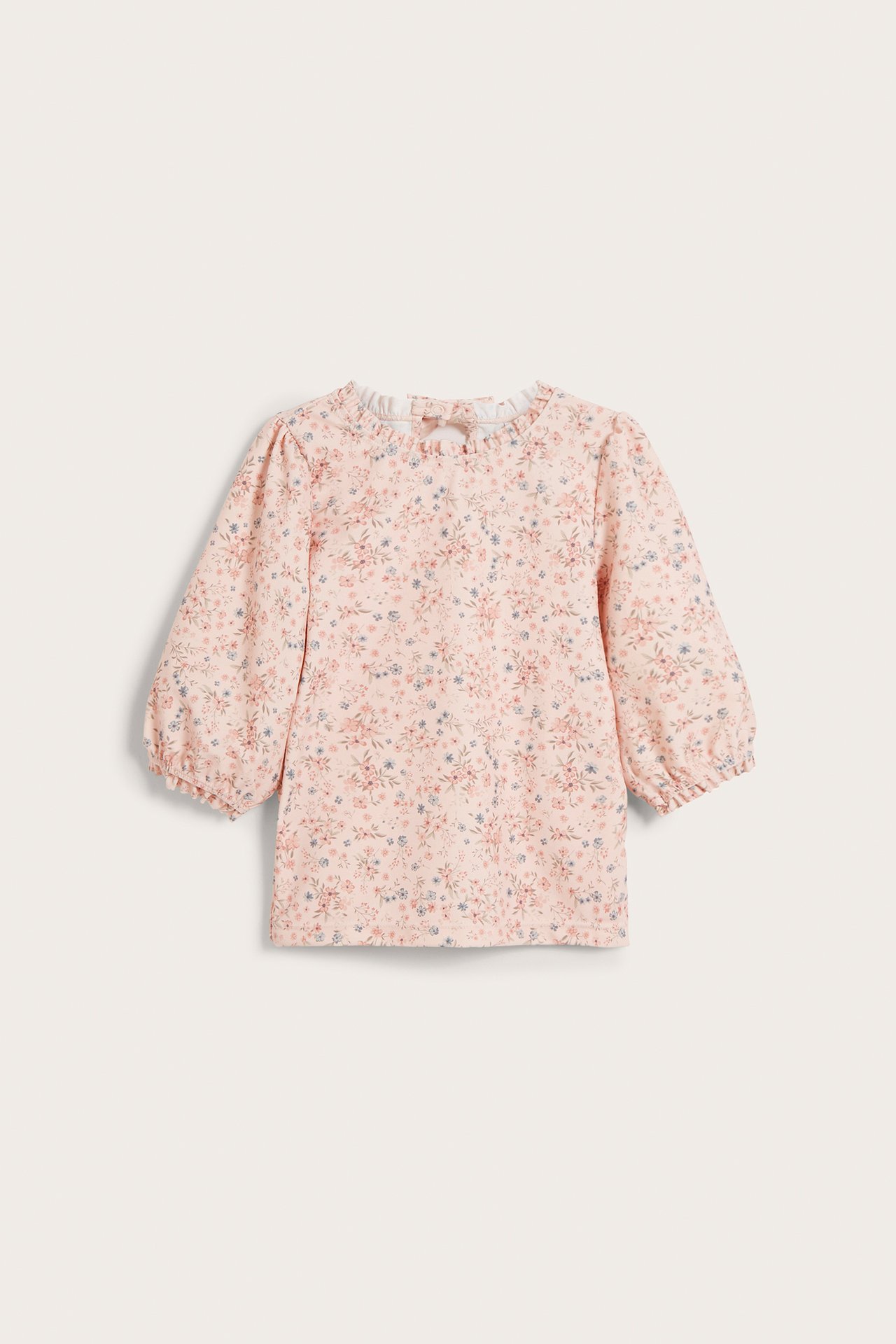 Front view of a baby's light pink floral UV top with 3/4 sleeves, ruffled neckline, and back bow.