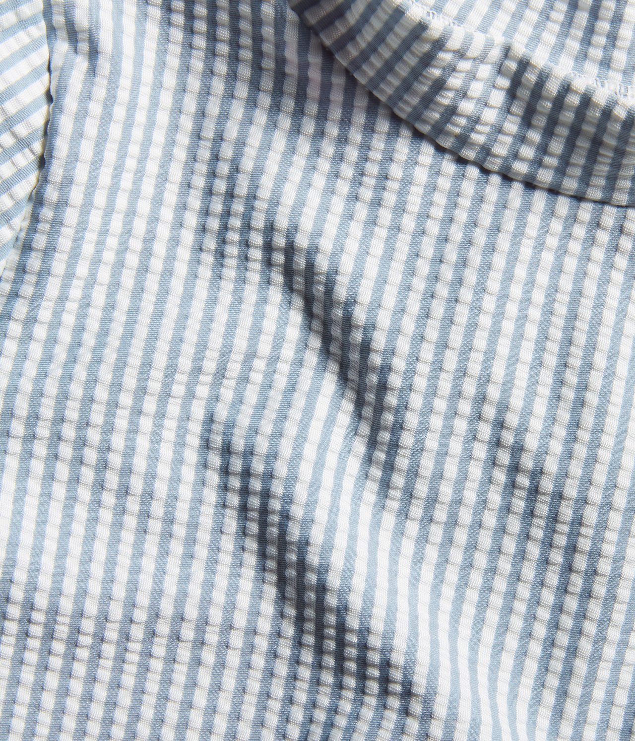 Close-up view of a blue and white striped seersucker UV top for kids.