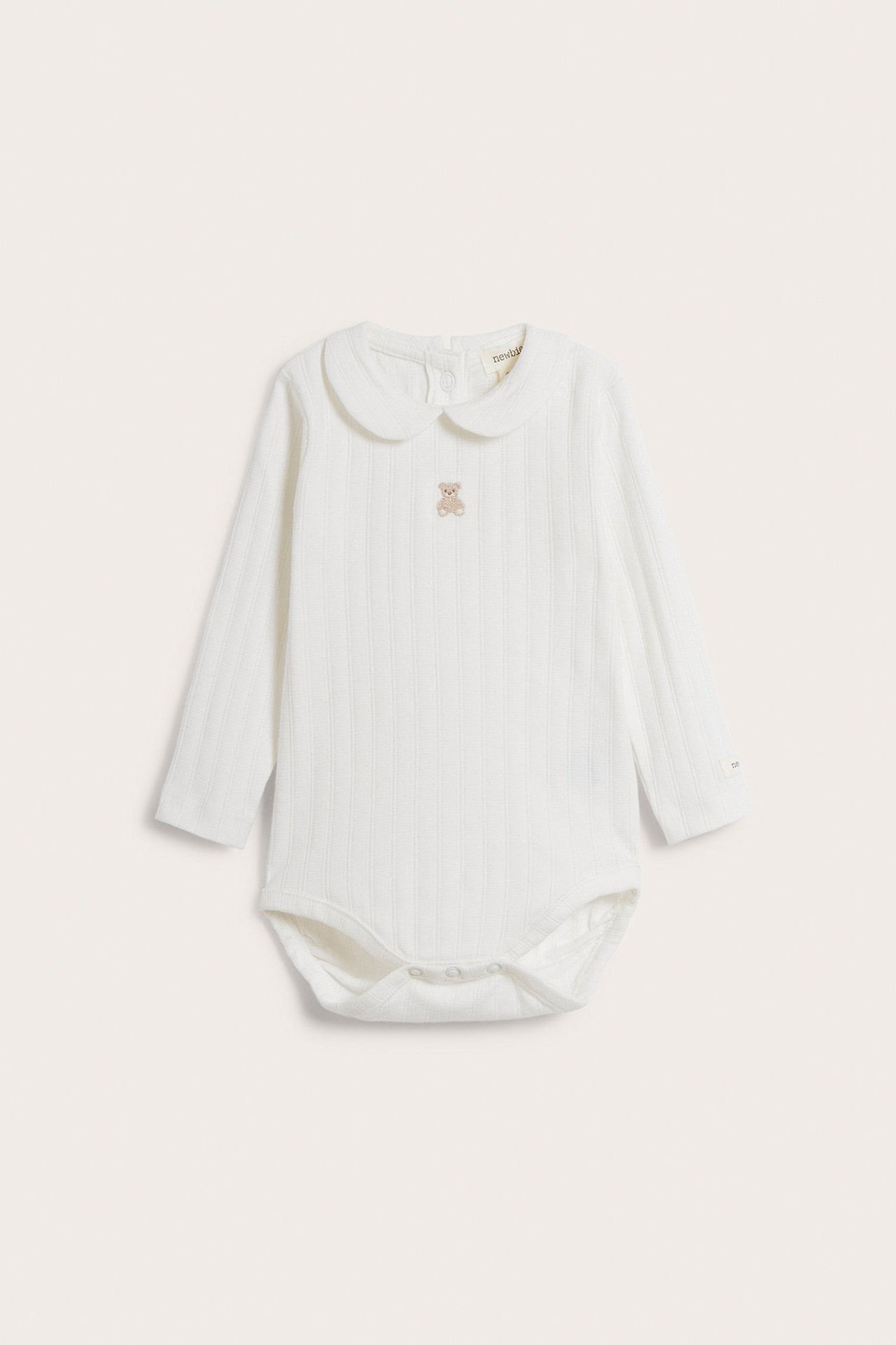 Front view of an off-white baby long-sleeved pointelle ribbed bodysuit with a collar and teddy bear embroidery.