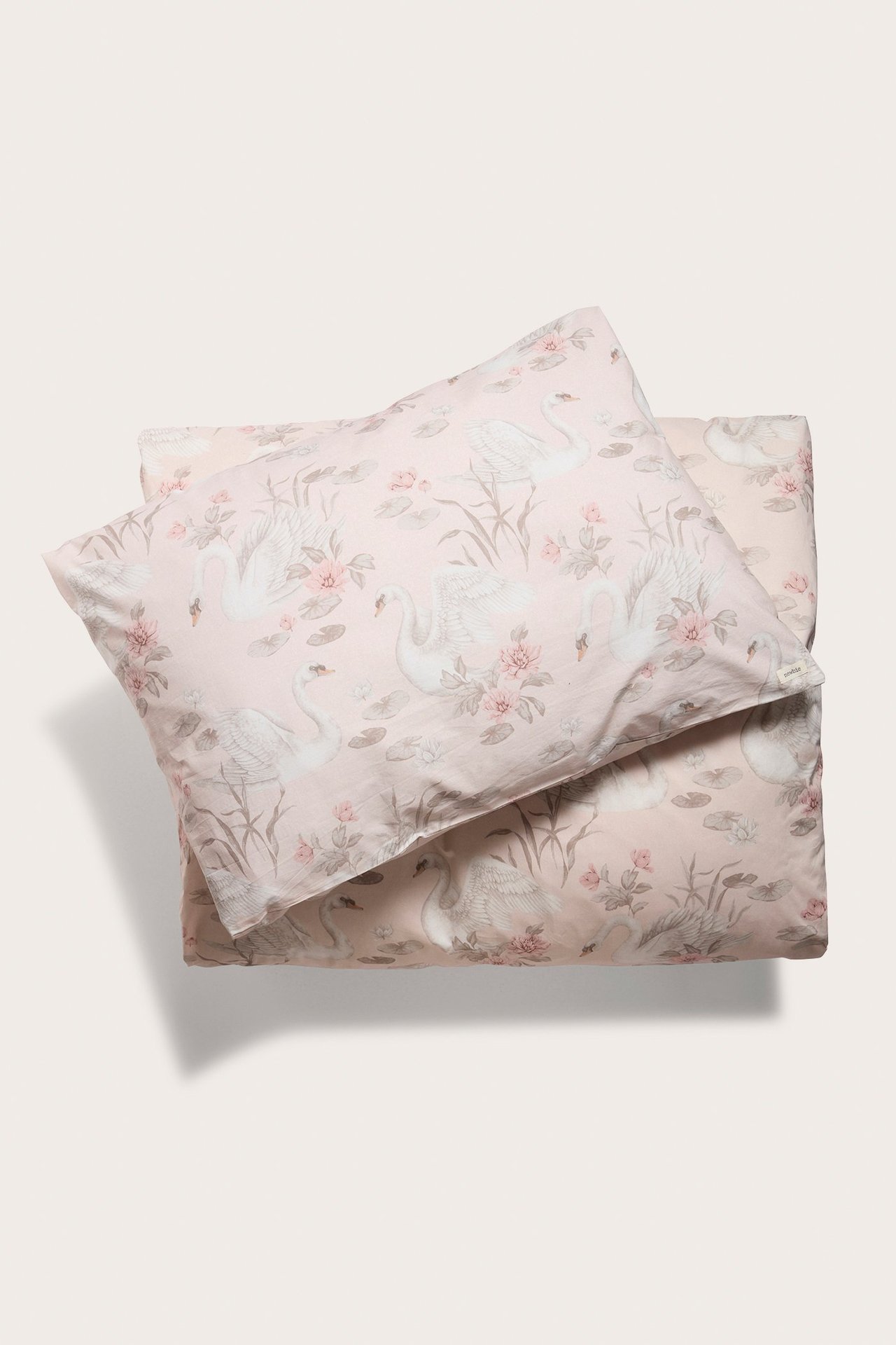 Draufsicht: Hellrosa Baumwoll-Bettwäsche mit Schwan- und Blumenmuster, Bettbezug und Kissenbezug.