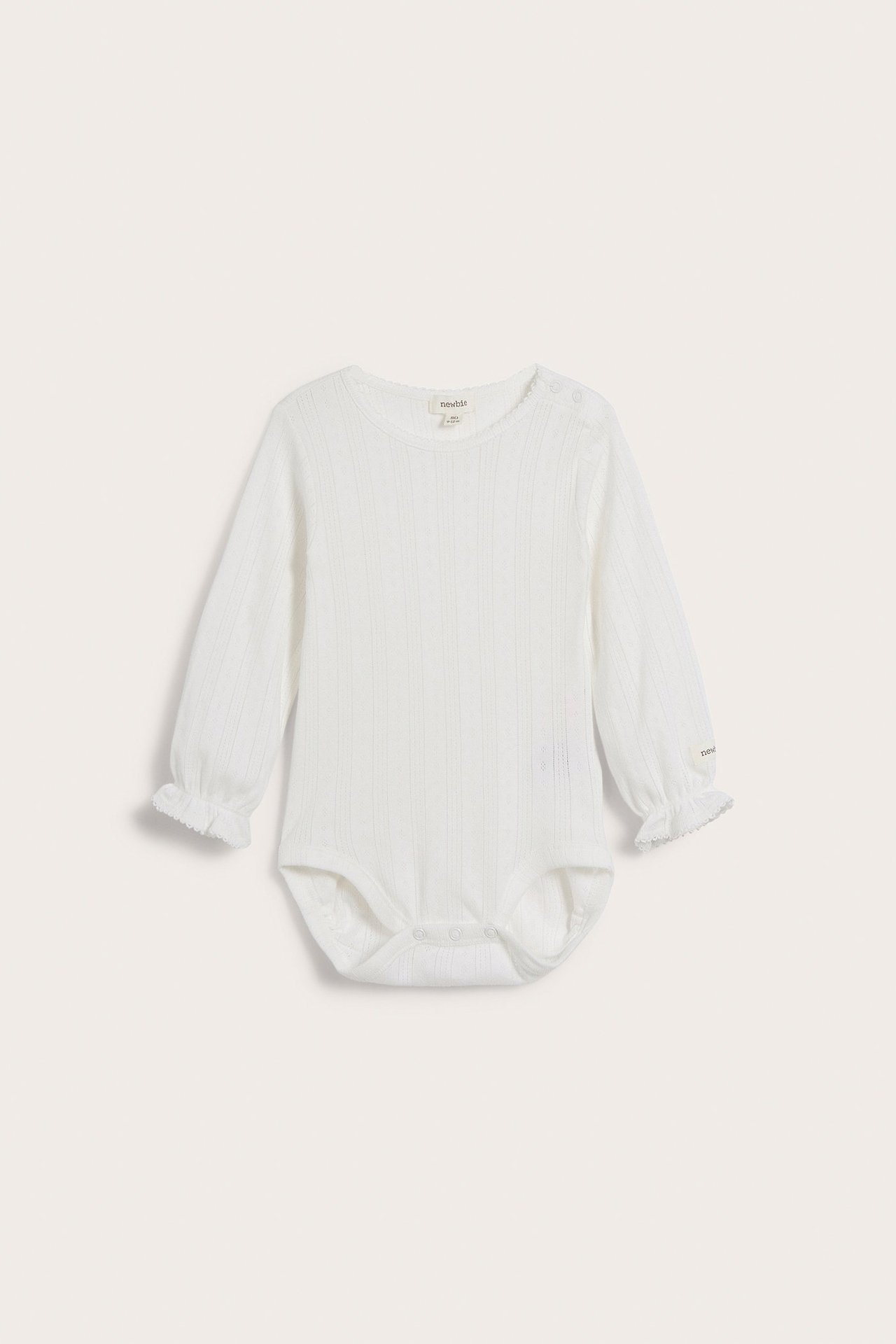 Front view of an offwhite pointelle ribbed baby bodysuit with ruffled cuffs and shoulder snap buttons.